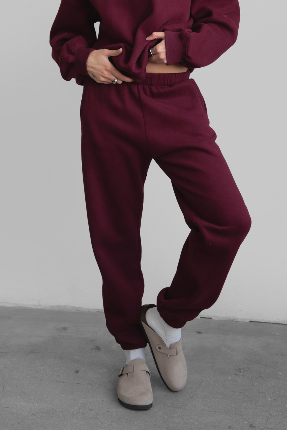 Woman wearing the TIC TOC PH26027 DOVE black cherry high waist sweatpants featuring an elastic waistband, deep side pockets, and tapered ankle hem with a matching top.
