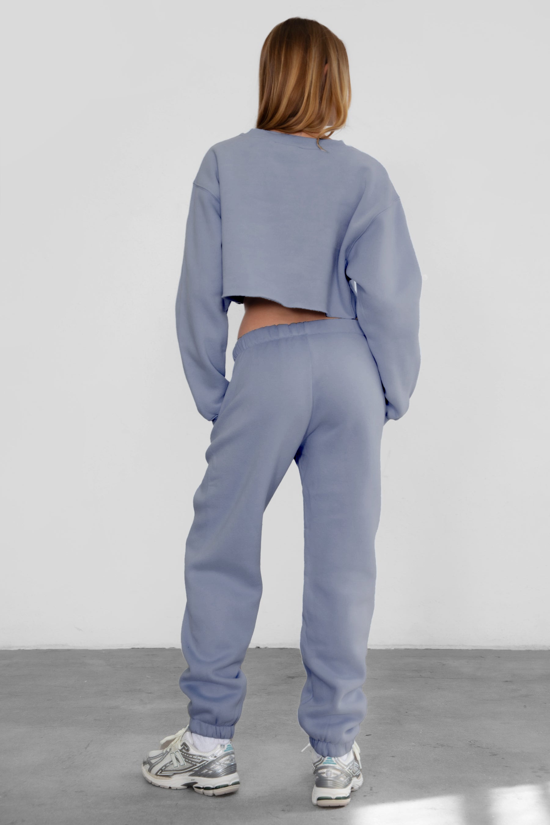 Woman wearing the TIC TOC PH26027 DOVE french blue high waist sweatpants featuring an elastic waistband, deep side pockets, and tapered ankle hem with a matching top.