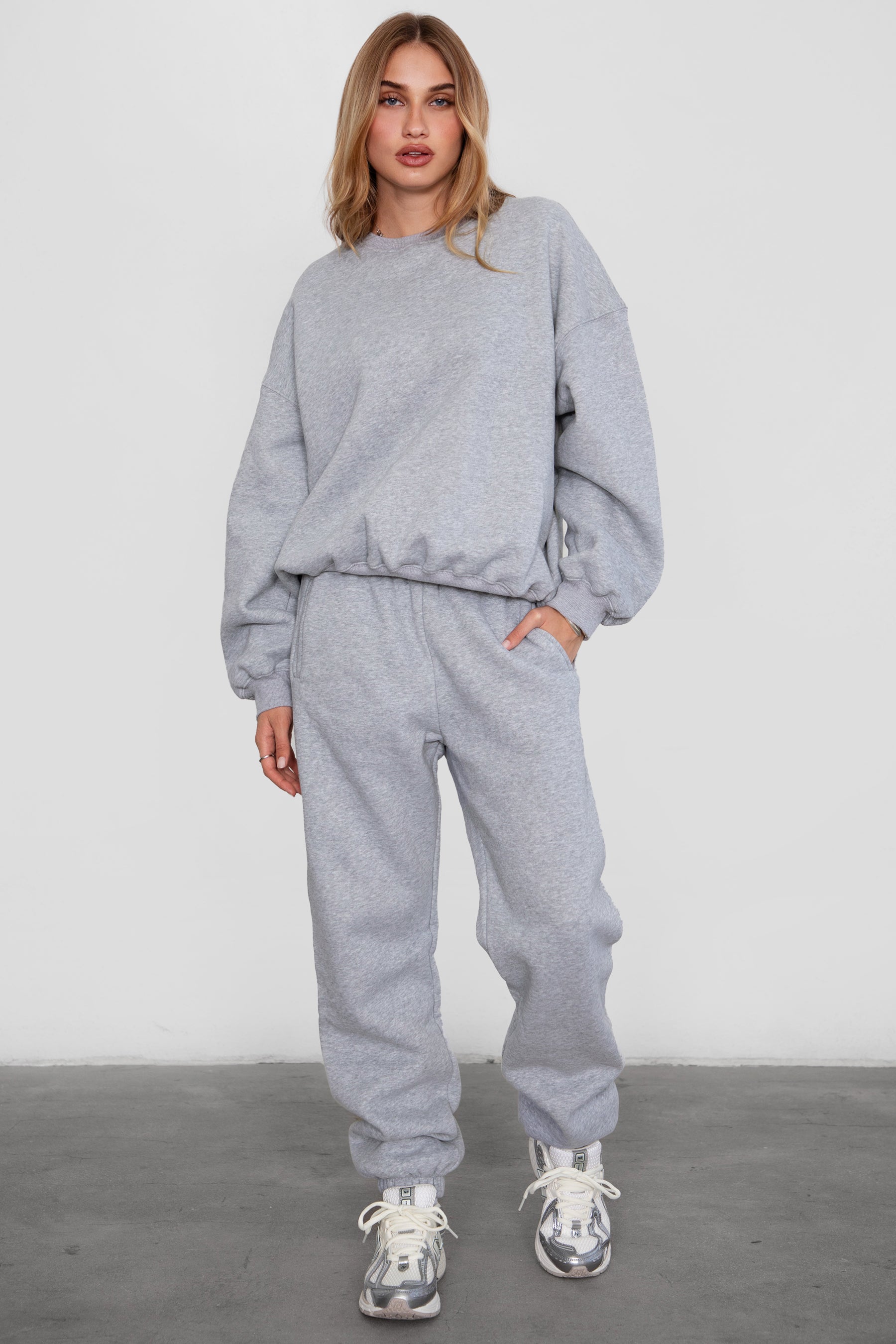 Woman wearing the TIC TOC PH26027 DOVE heather grey high waist sweatpants featuring an elastic waistband, deep side pockets, and tapered ankle hem with a matching top.