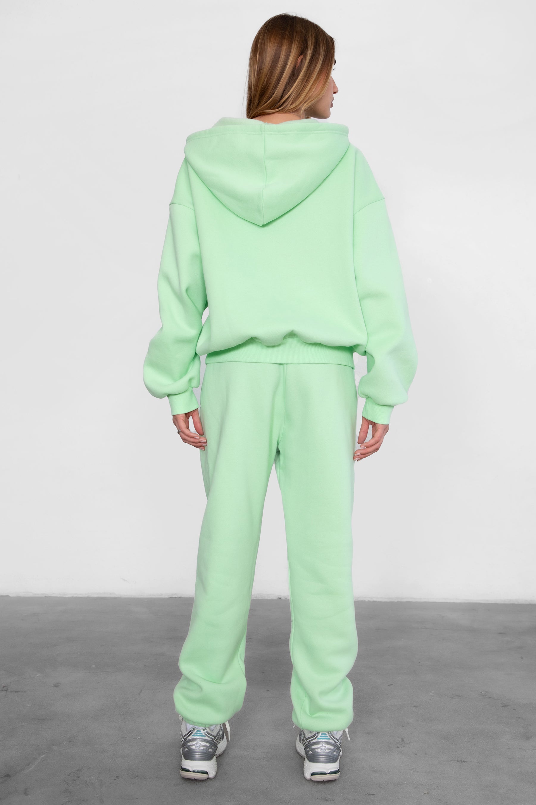 Woman wearing the TIC TOC PH26027 DOVE pastel lime high waist sweatpants featuring an elastic waistband, deep side pockets, and tapered ankle hem with a matching top.