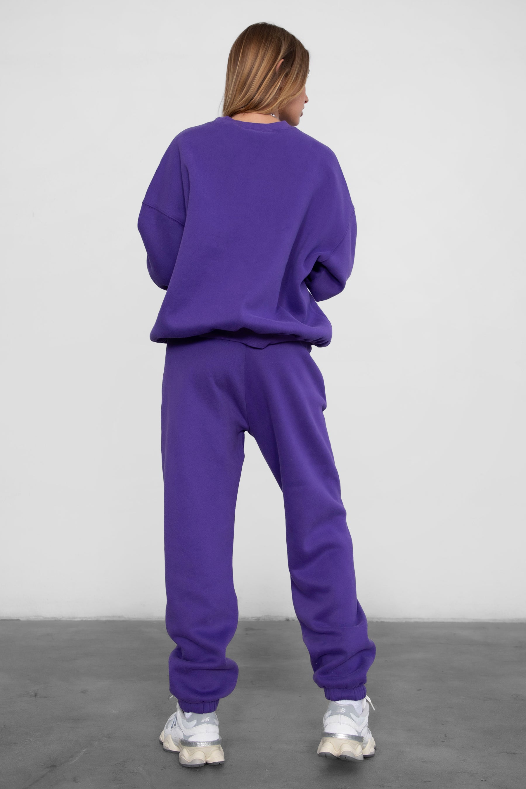 Woman wearing the TIC TOC PH26027 DOVE purple high waist sweatpants featuring an elastic waistband, deep side pockets, and tapered ankle hem with a matching top.