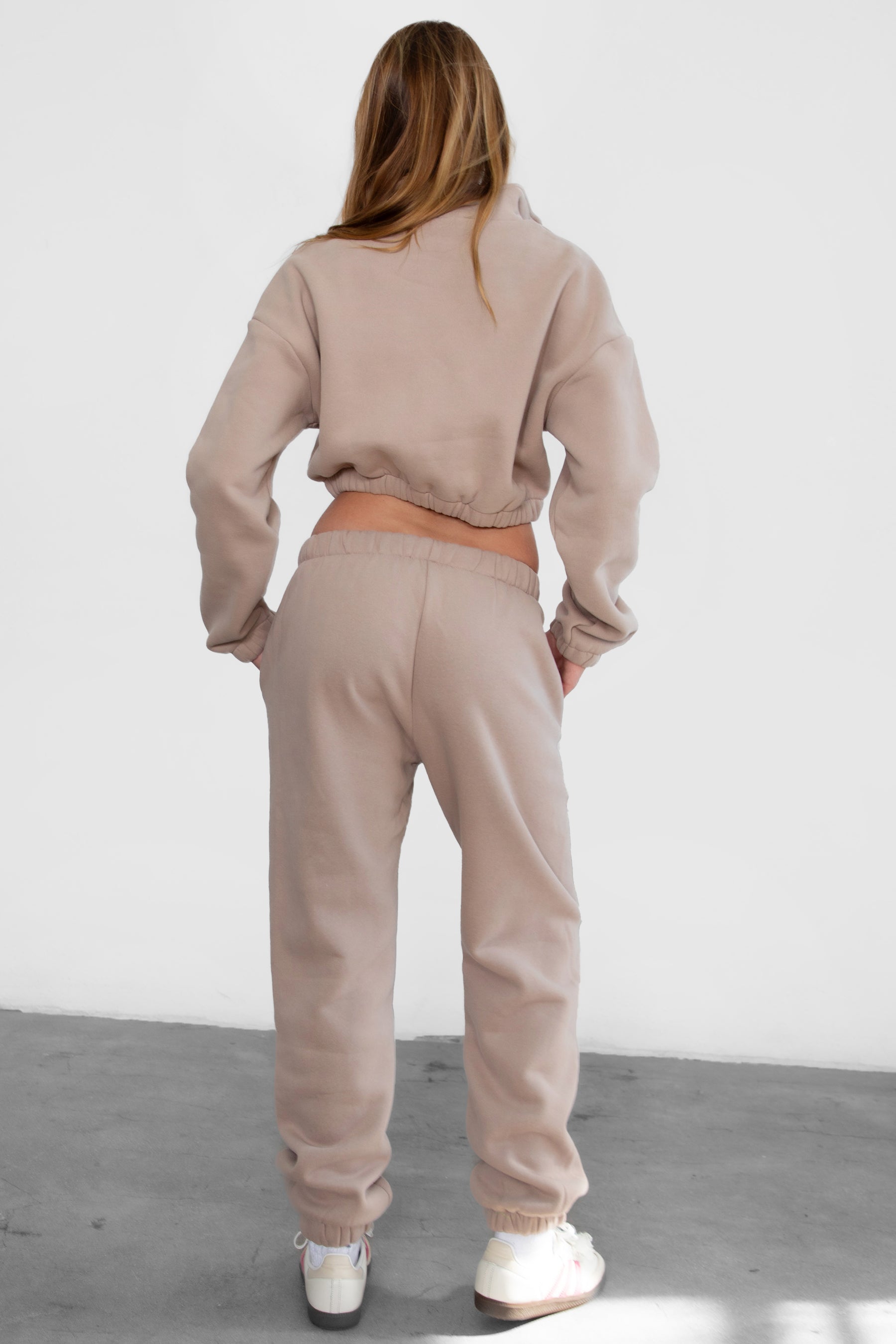 Woman wearing the TIC TOC PH26027 DOVE taupe high waist sweatpants featuring an elastic waistband, deep side pockets, and tapered ankle hem with a matching top.