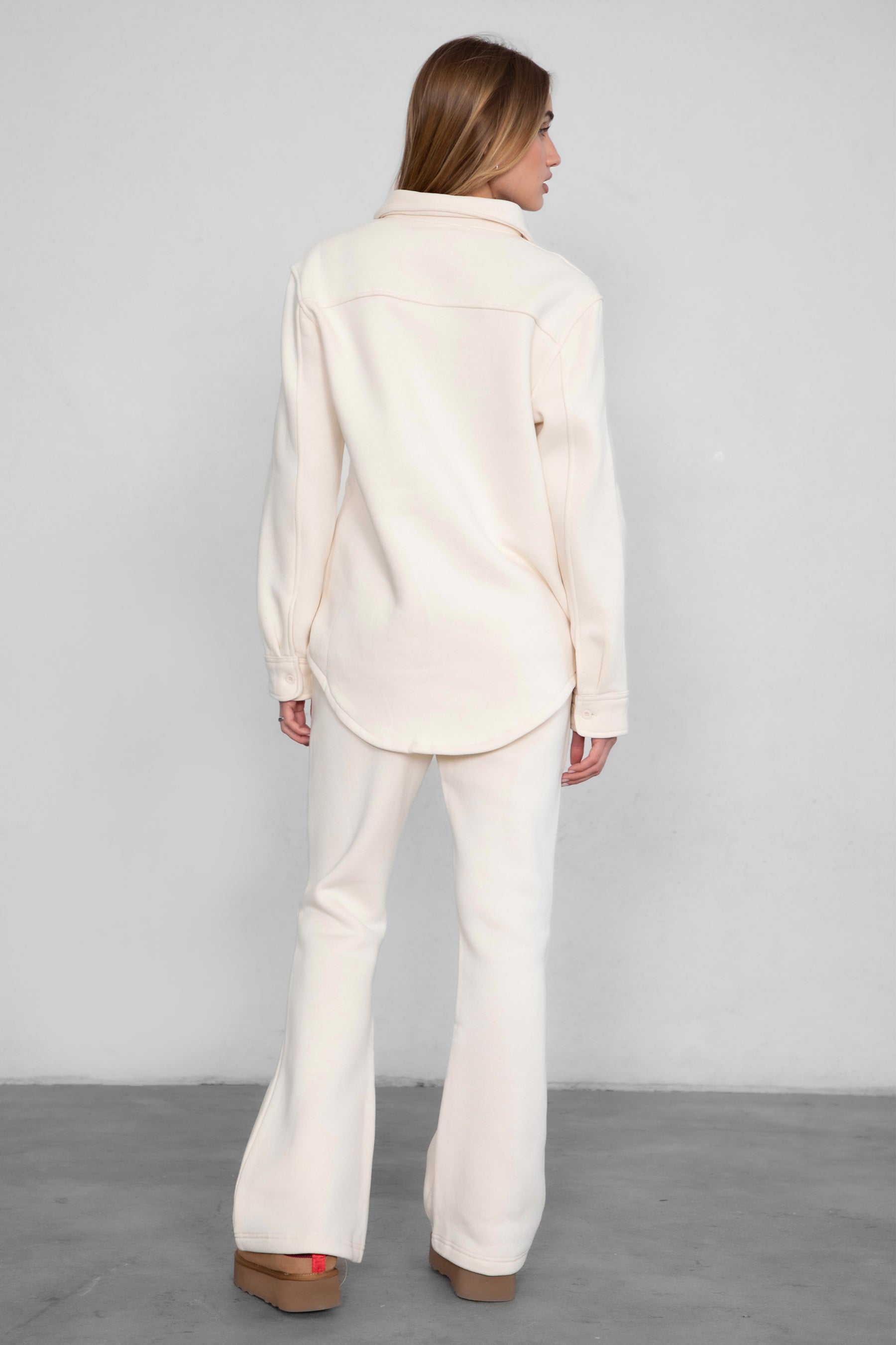 Woman wearing TIC TOC PH29142 JIYA essential fleece flare sweatpants with mid-rise waistband and side pockets from plush fleece collection in ecru paired with a matching shacket.