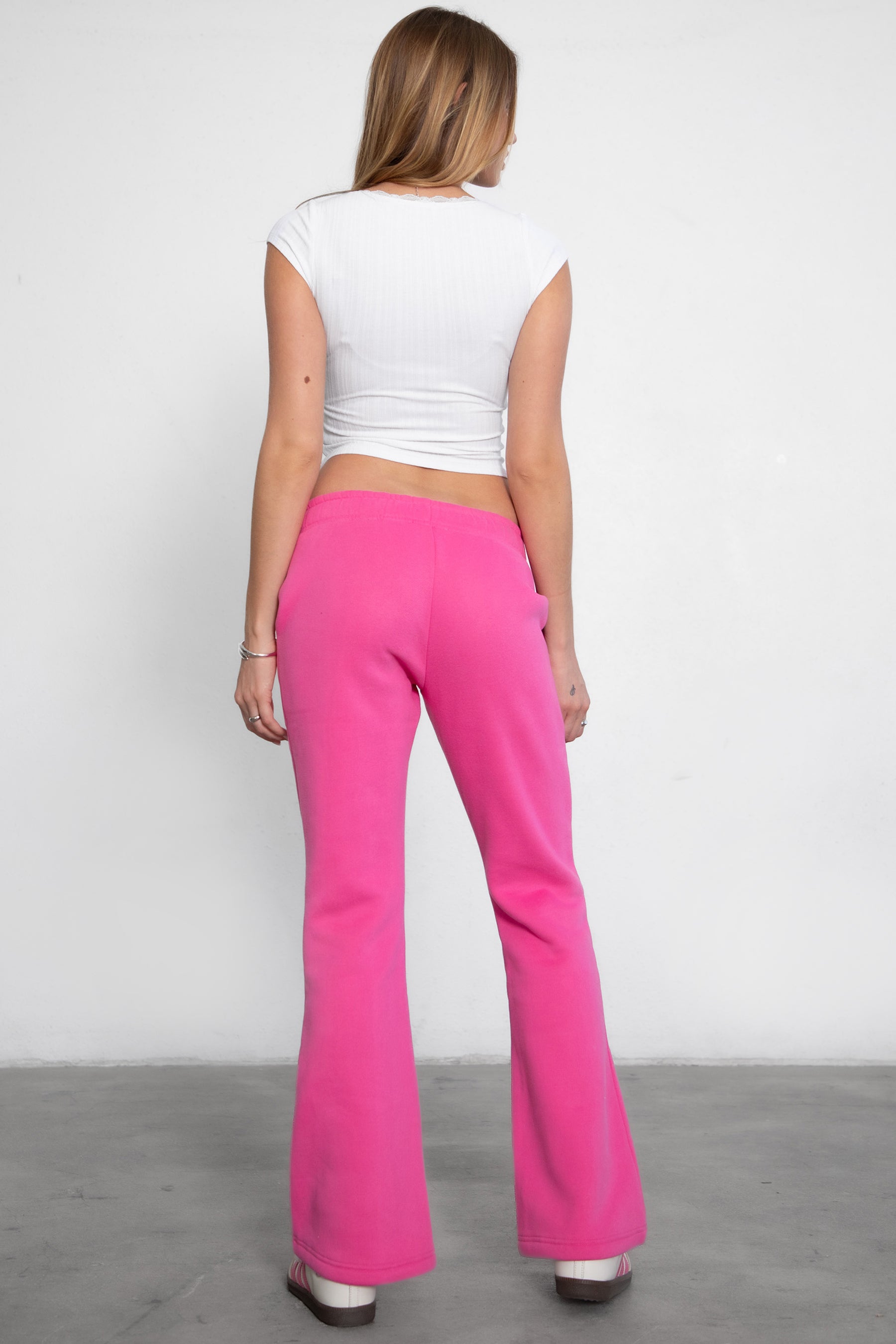 Woman wearing TIC TOC PH29142 JIYA essential fleece flare sweatpants with mid-rise waistband and side pockets from plush fleece collection in fuchsia paired with a white top.