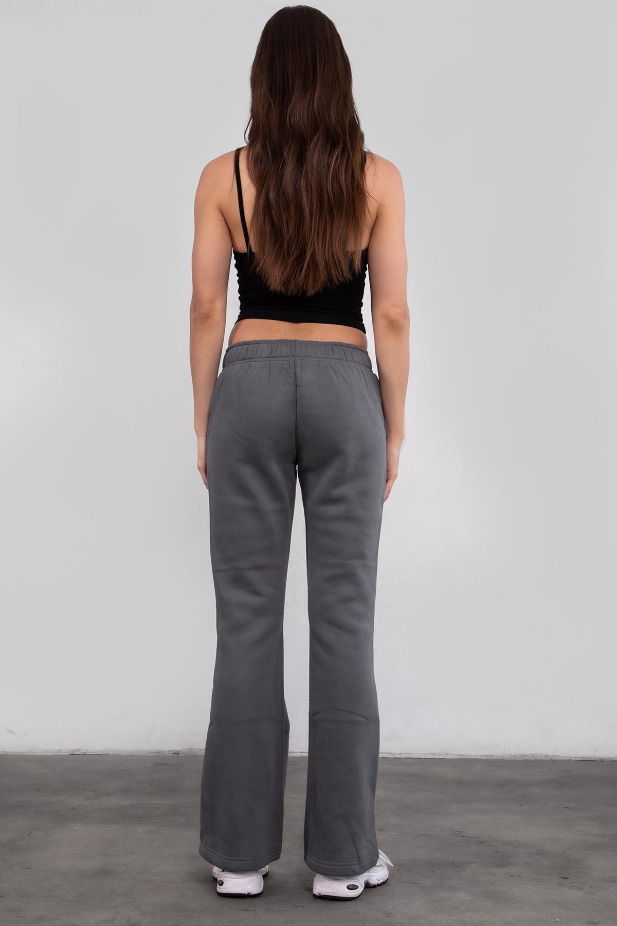 Woman wearing TIC TOC PH29142 JIYA essential fleece flare sweatpants with mid-rise waistband and side pockets from plush fleece collection in graphite paired with a black cami top.