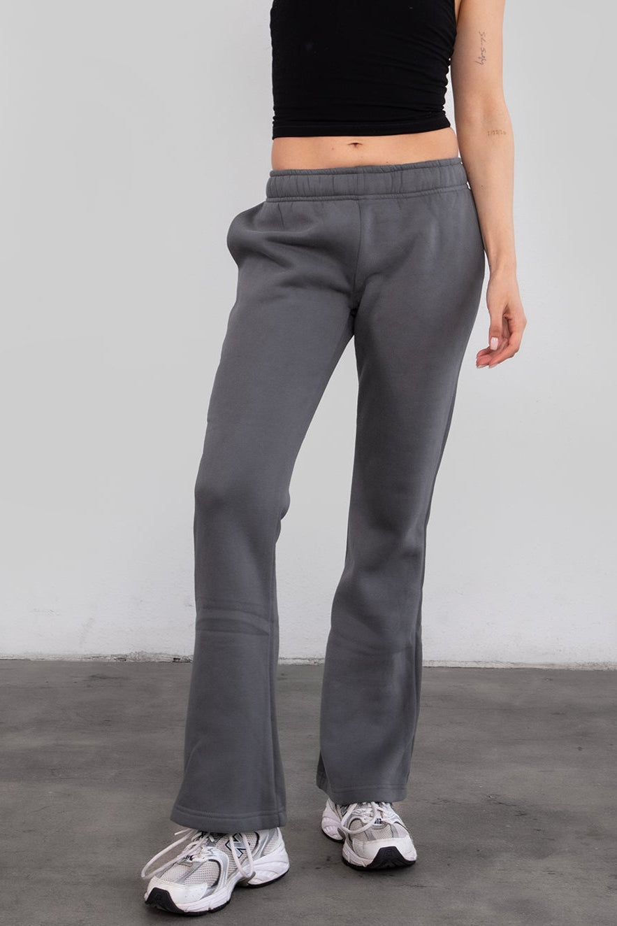 Woman wearing TIC TOC PH29142 JIYA essential fleece flare sweatpants with mid-rise waistband and side pockets from plush fleece collection in graphite paired with a black cami top.