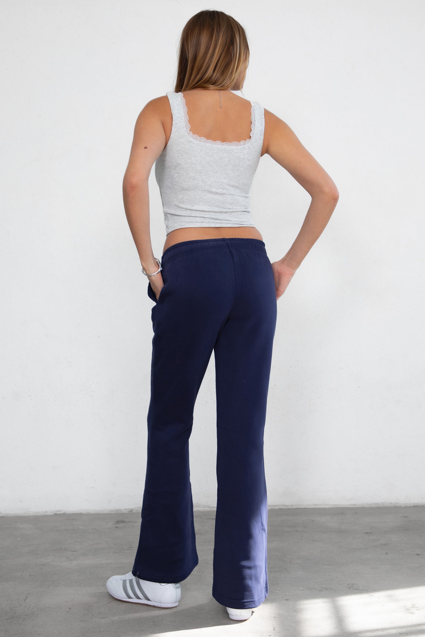 Woman wearing TIC TOC PH29142 JIYA essential fleece flare sweatpants with mid-rise waistband and side pockets from plush fleece collection in navy paired with a heather white top.