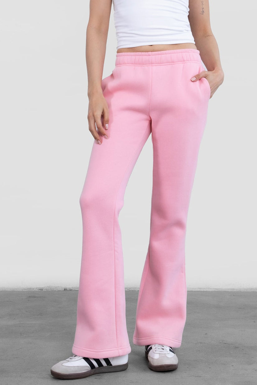 Woman wearing TIC TOC PH29142 JIYA essential fleece flare sweatpants with mid-rise waistband and side pockets from plush fleece collection in blush paired with a white bandeau top.
