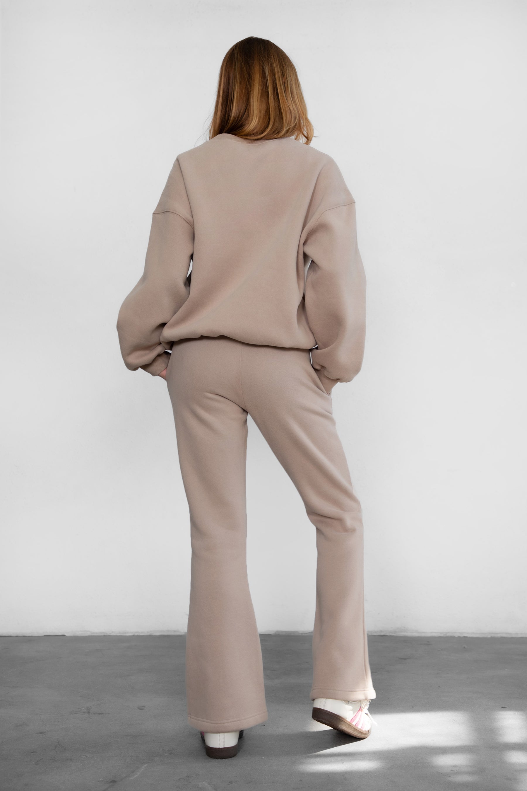 Woman wearing TIC TOC PH29142 JIYA essential fleece flare sweatpants with mid-rise waistband and side pockets from plush fleece collection in taupe paired with a matching crew neck