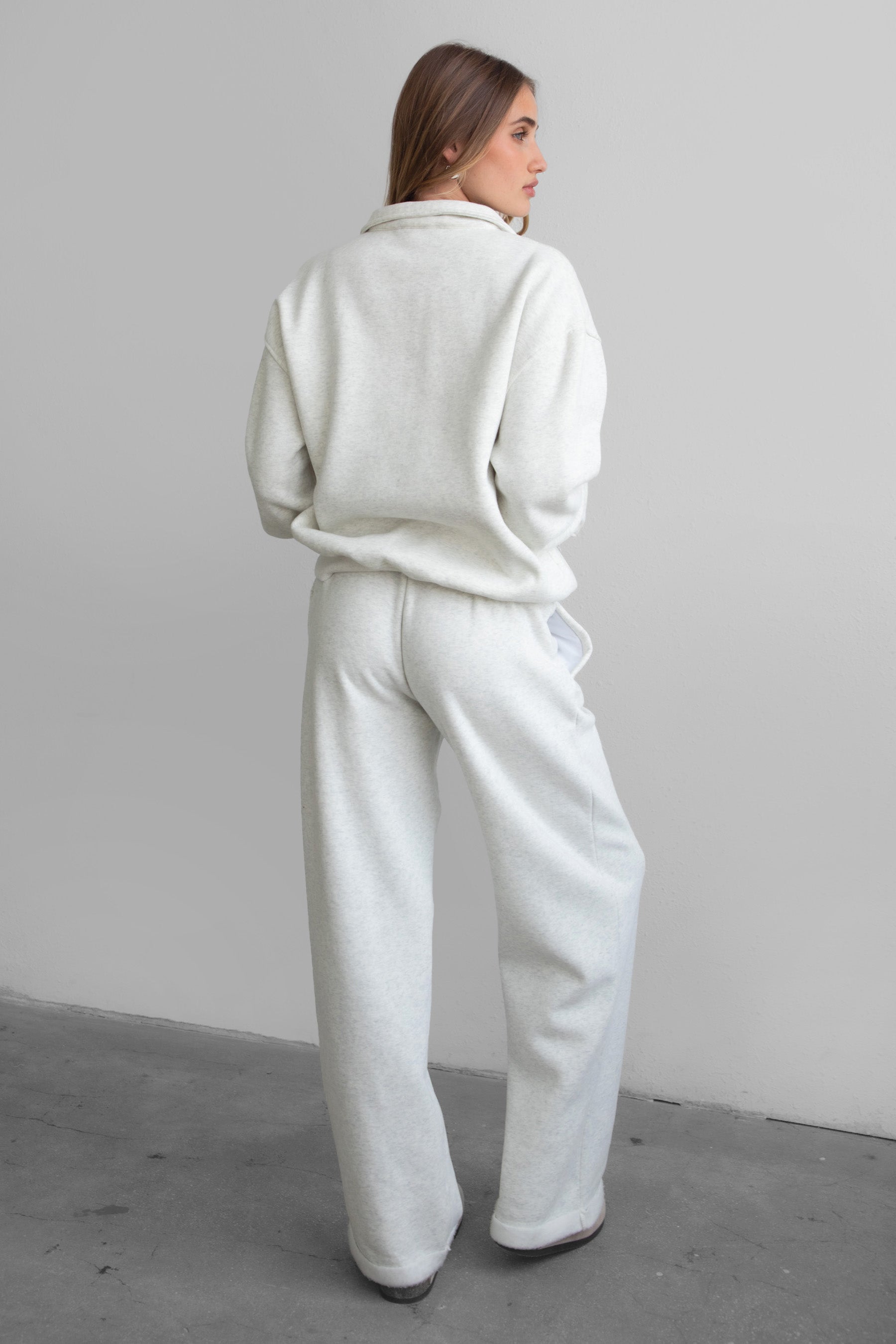 Woman wearing the TIC TOC PJ30241 LANI heather white cloud fleece wide leg sweatpants featuring a straight leg silhouette, drawcord waistband, and side pockets paired with a matching half zip sweater.