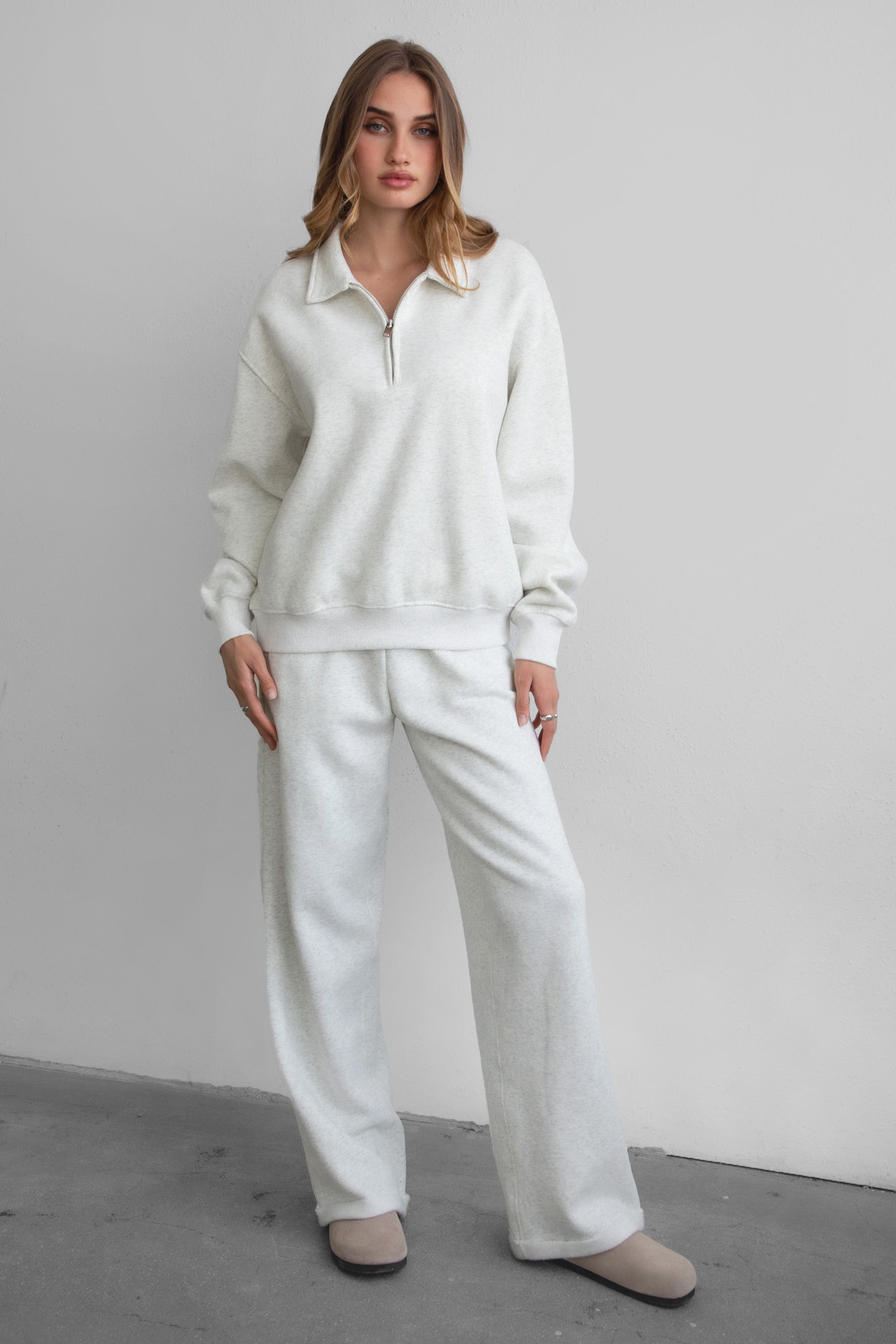 Woman wearing the TIC TOC PJ30241 LANI heather white cloud fleece wide leg sweatpants featuring a straight leg silhouette, drawcord waistband, and side pockets paired with a matching half zip sweater.