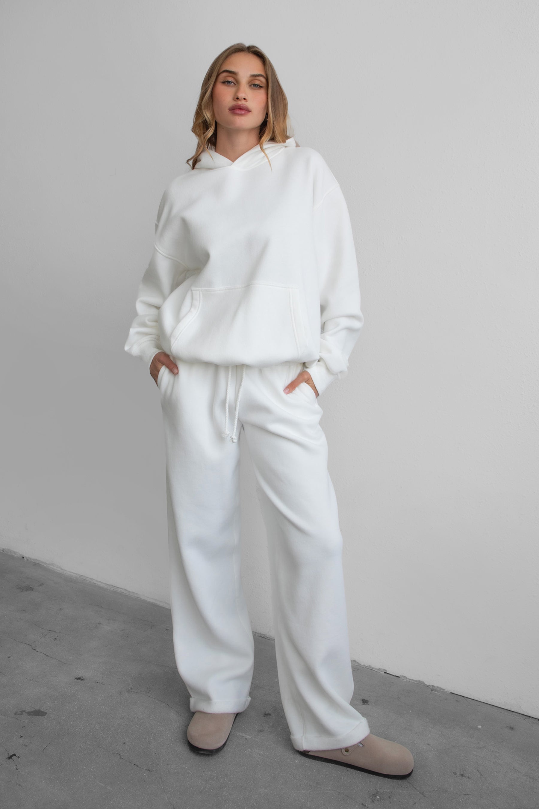 Woman wearing the TIC TOC PJ30241 LANI white cloud fleece wide leg sweatpants featuring a straight leg silhouette, drawcord waistband, and side pockets paired with a matching hoodie.