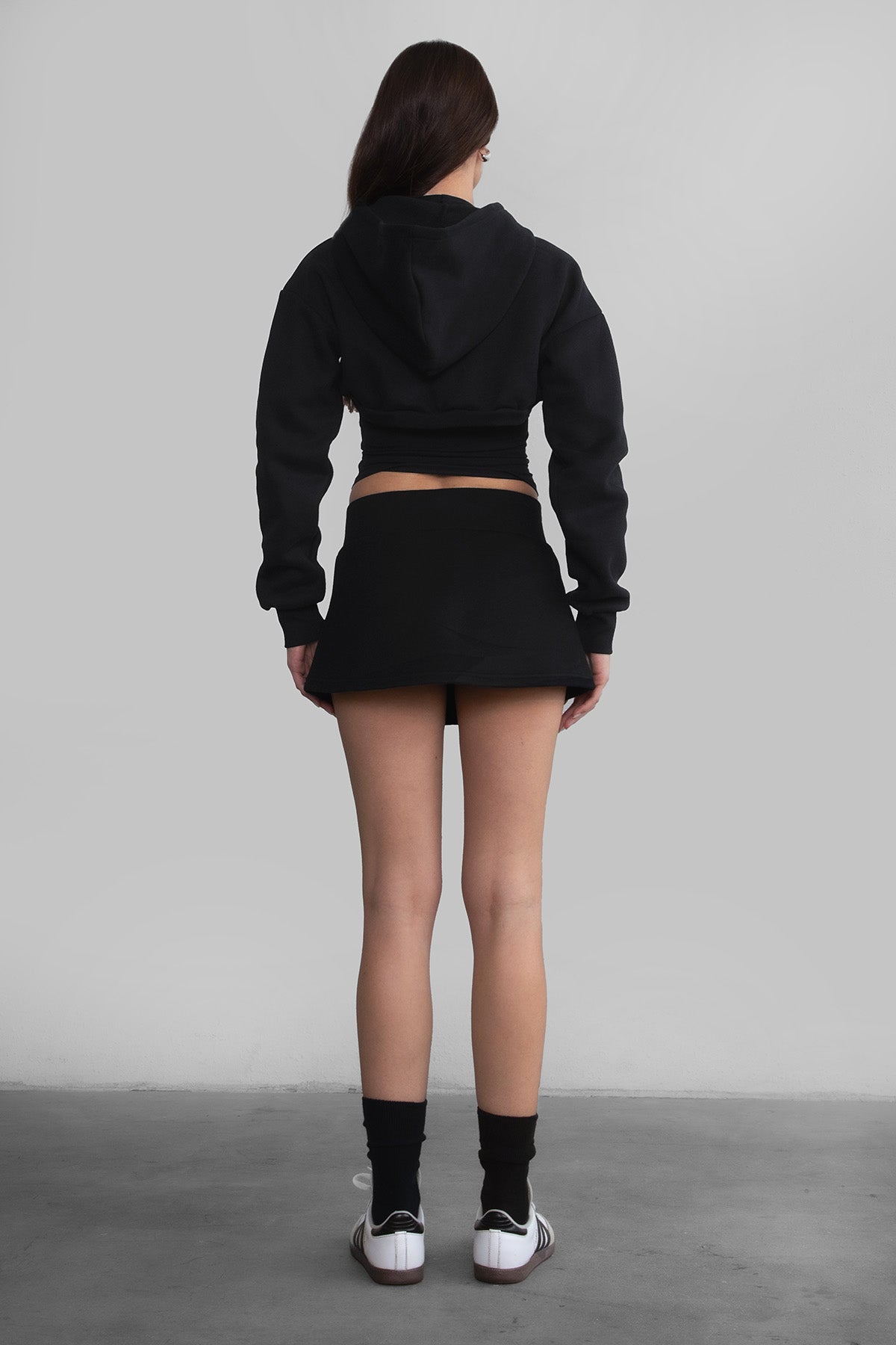 Woman wearing the TIC TOC SH30133BA JEMMA black fleece mini skirt featuring an elastic waistband, drawstring closure, and hidden shorts for comfort and coverage paired with a matching top.