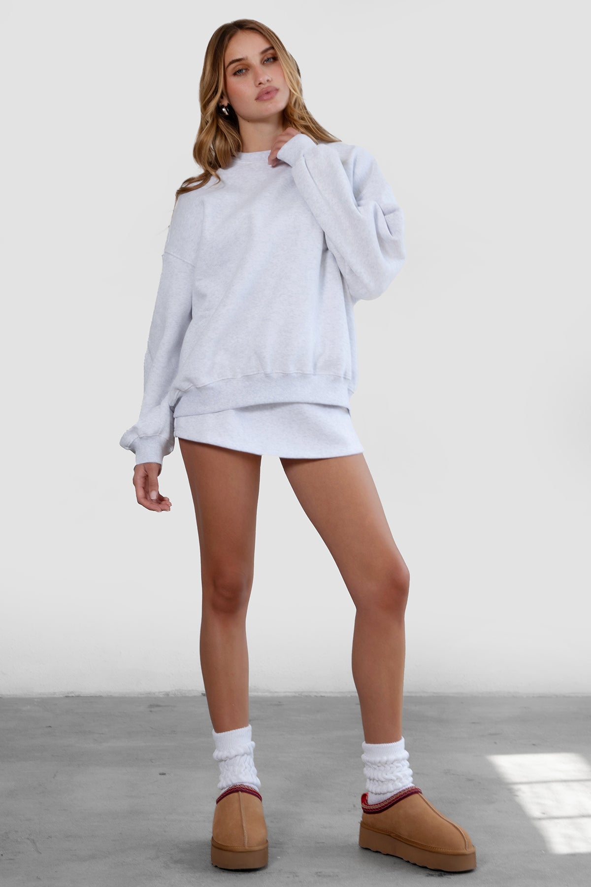 Woman wearing the TIC TOC TH28243 VARSITY ash fleece crew neck pullover sweatshirt featuring dropped shoulders, ribbed trim, and plush fleece fabric with the matching bottoms