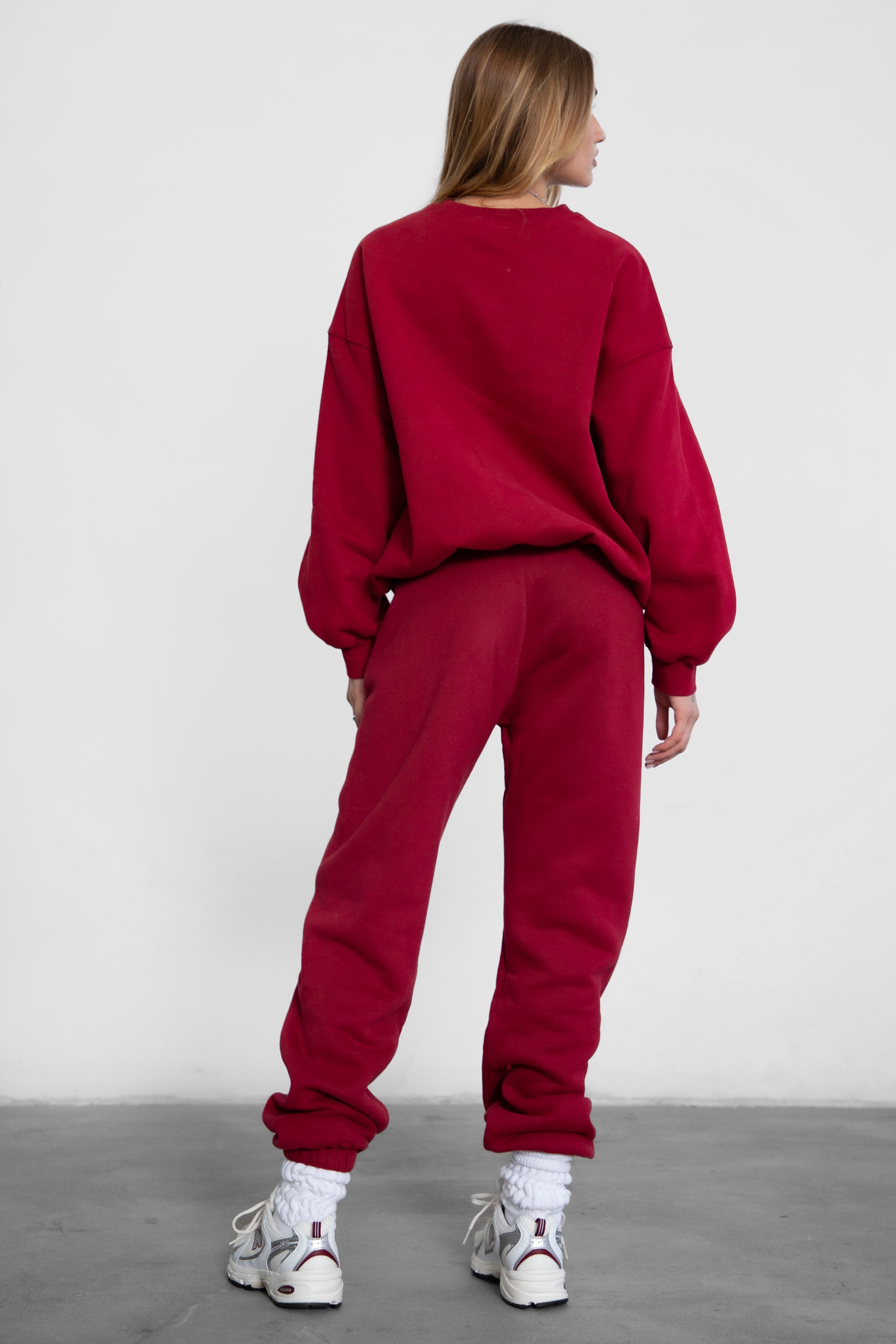 Woman wearing the TIC TOC TH28243 VARSITY burgundy fleece crew neck pullover sweatshirt featuring dropped shoulders, ribbed trim, and plush fleece fabric with the matching bottoms