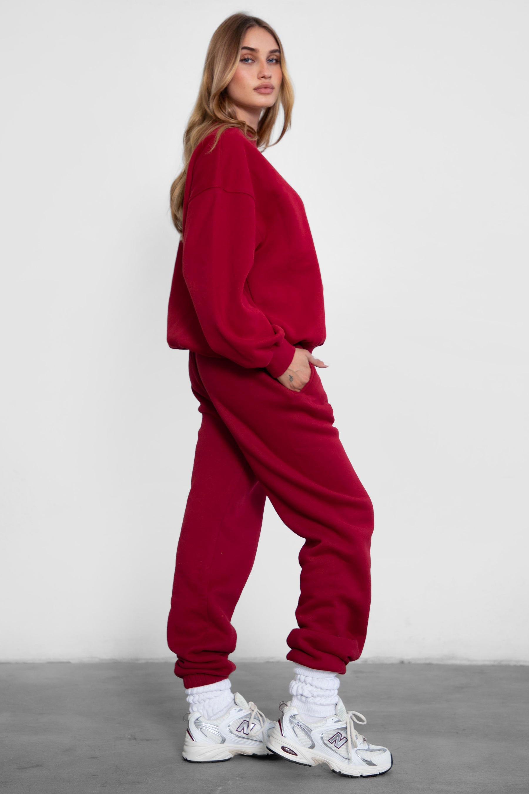 Woman wearing the TIC TOC TH28243 VARSITY burgundy fleece crew neck pullover sweatshirt featuring dropped shoulders, ribbed trim, and plush fleece fabric with the matching bottoms