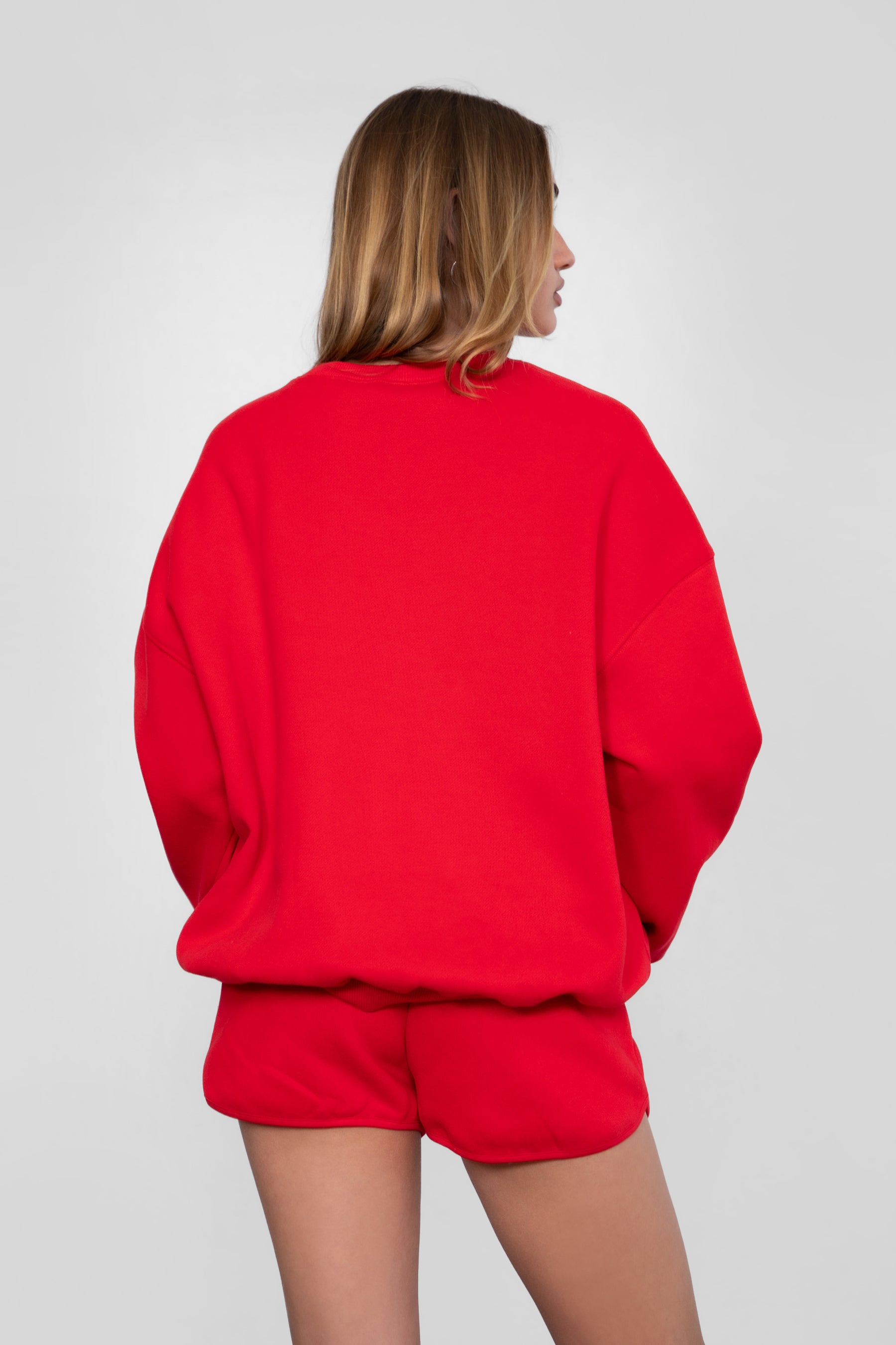 Woman wearing the TIC TOC TH28243 VARSITY cherry red fleece crew neck pullover sweatshirt featuring dropped shoulders, ribbed trim, and plush fleece fabric with the matching bottoms