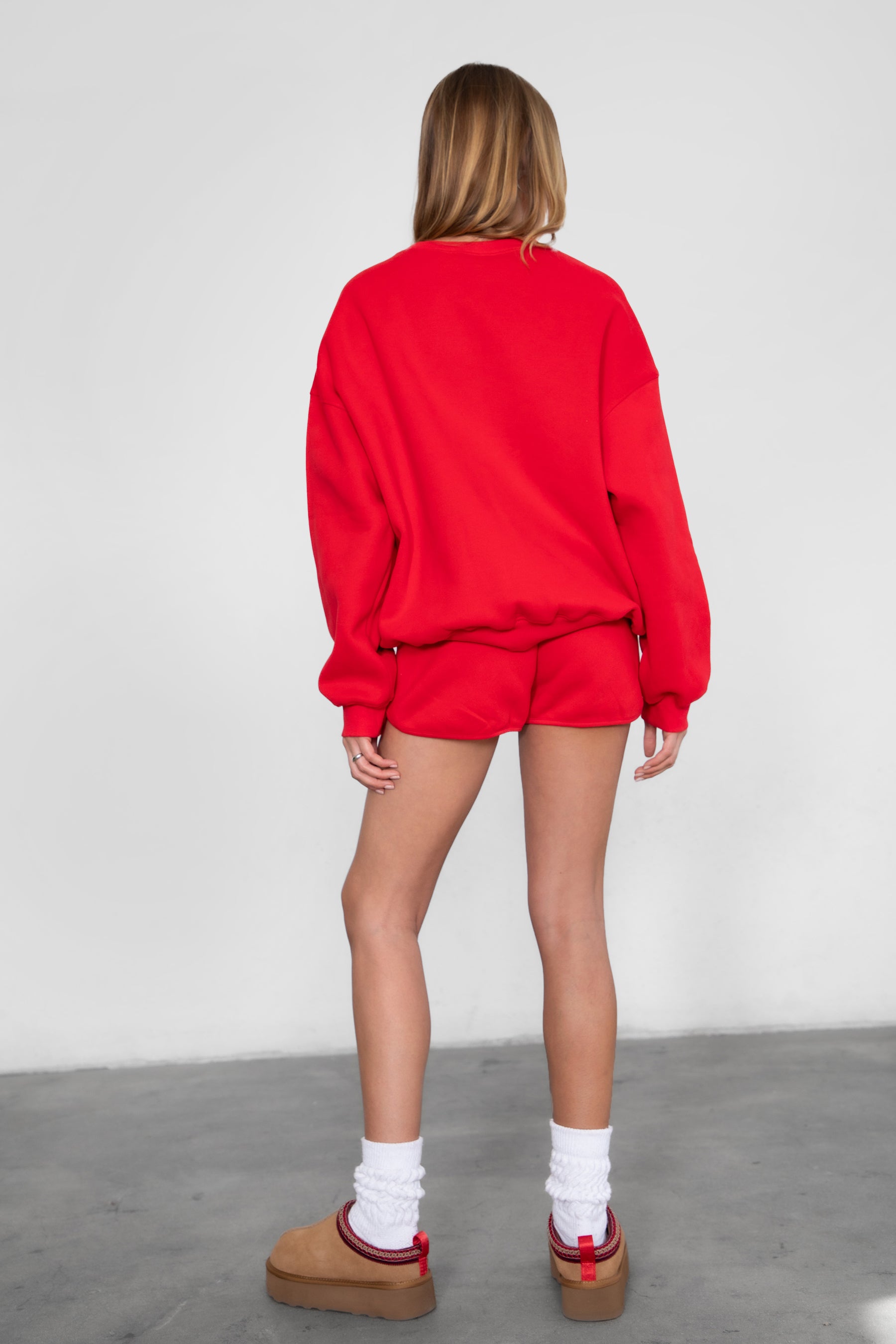 Woman wearing the TIC TOC TH28243 VARSITY cherry red fleece crew neck pullover sweatshirt featuring dropped shoulders, ribbed trim, and plush fleece fabric with the matching bottoms