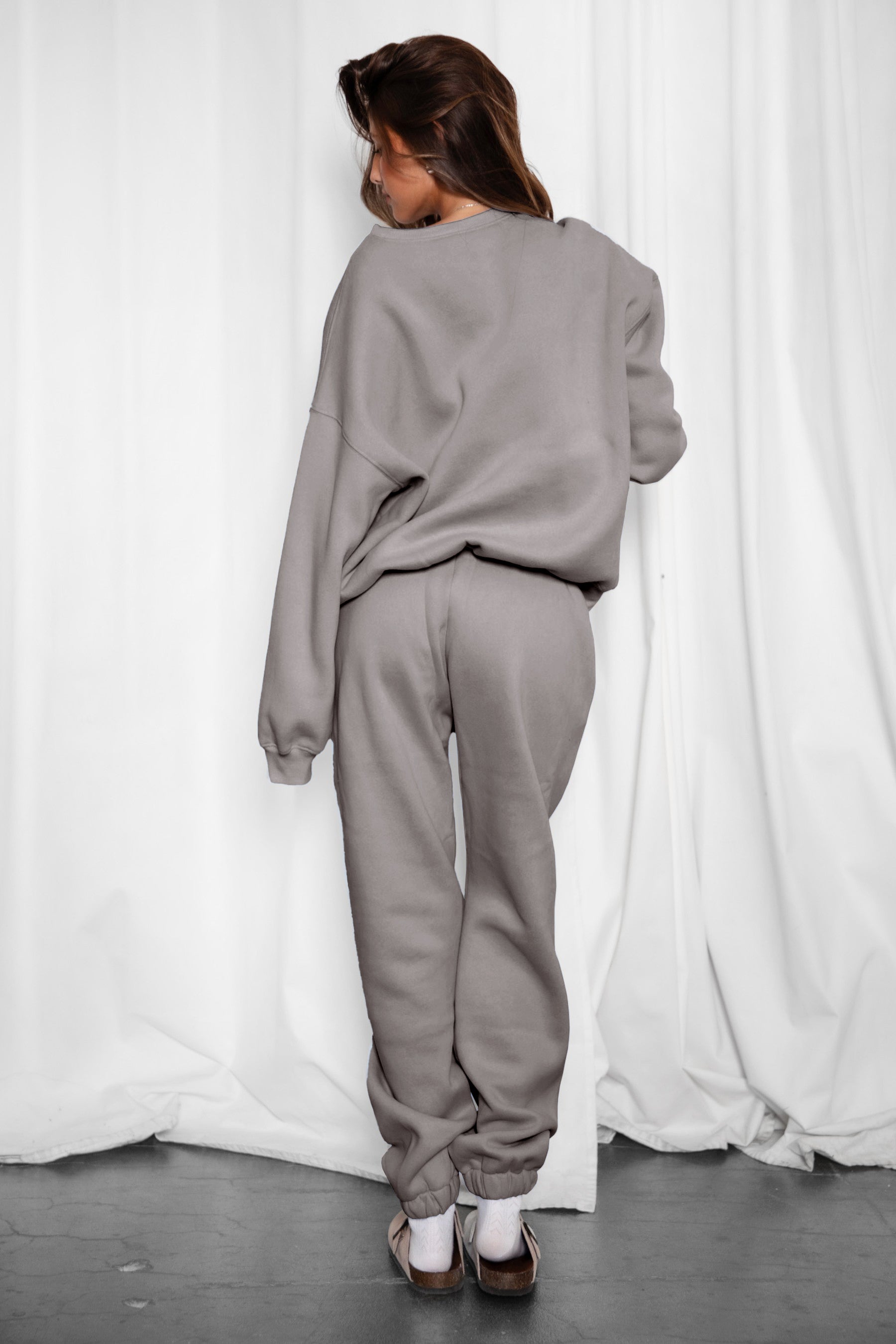 Woman wearing the TIC TOC TH28243 VARSITY grey fleece crew neck pullover sweatshirt featuring dropped shoulders, ribbed trim, and plush fleece fabric with the matching bottoms