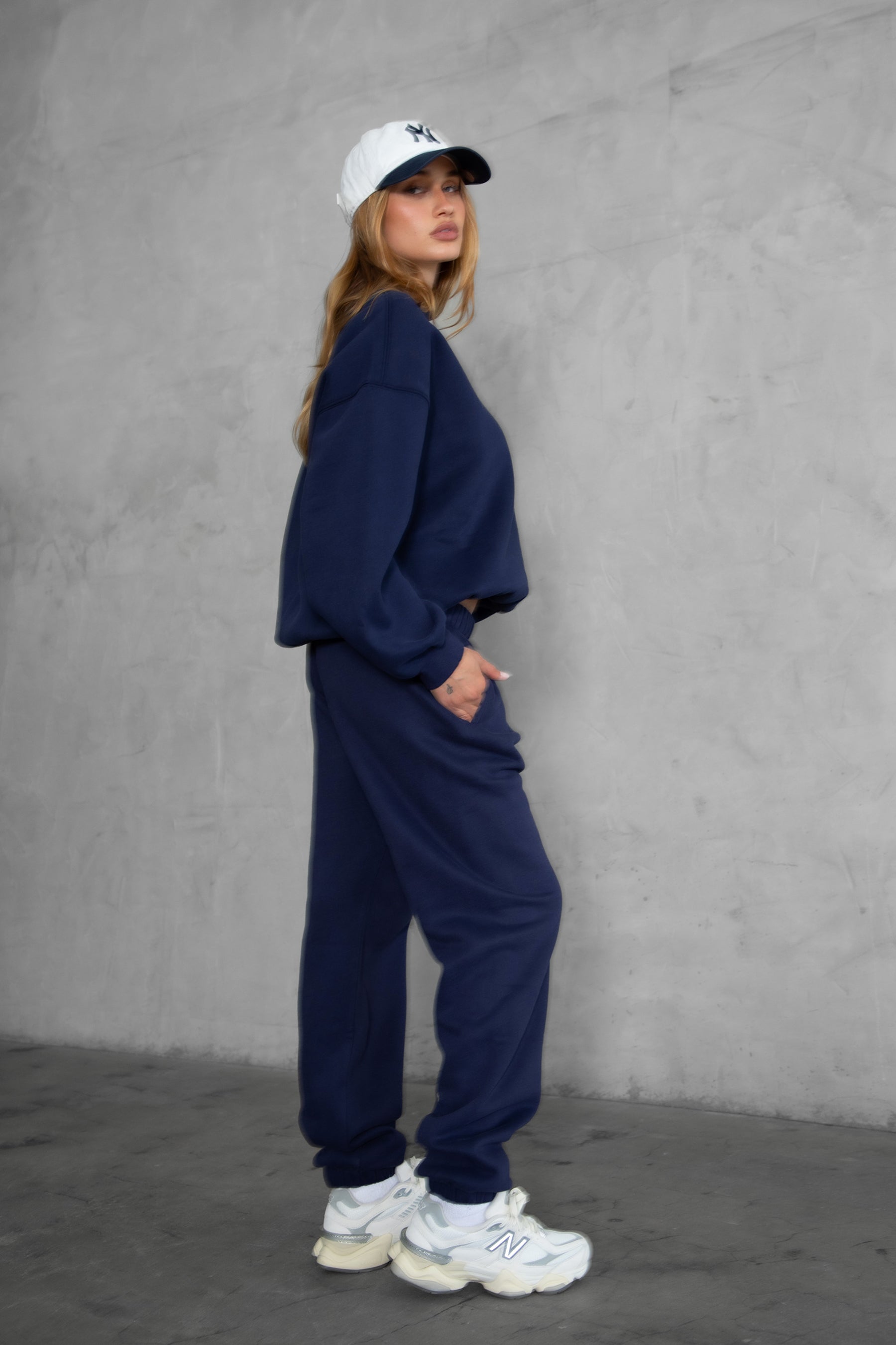 Woman wearing the TIC TOC TH28243 VARSITY navy blue fleece crew neck pullover sweatshirt featuring dropped shoulders, ribbed trim, and plush fleece fabric with the matching bottoms