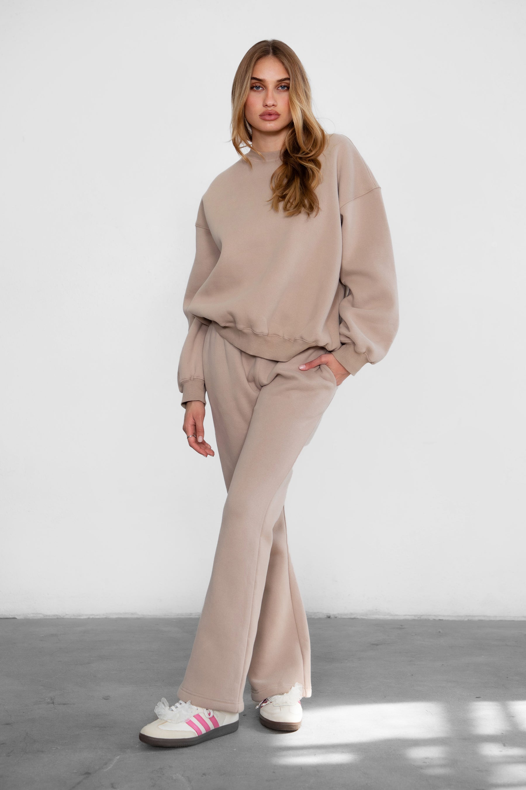 Woman wearing the TIC TOC TH28243 VARSITY taupe fleece crew neck pullover sweatshirt featuring dropped shoulders, ribbed trim, and plush fleece fabric with the matching bottoms