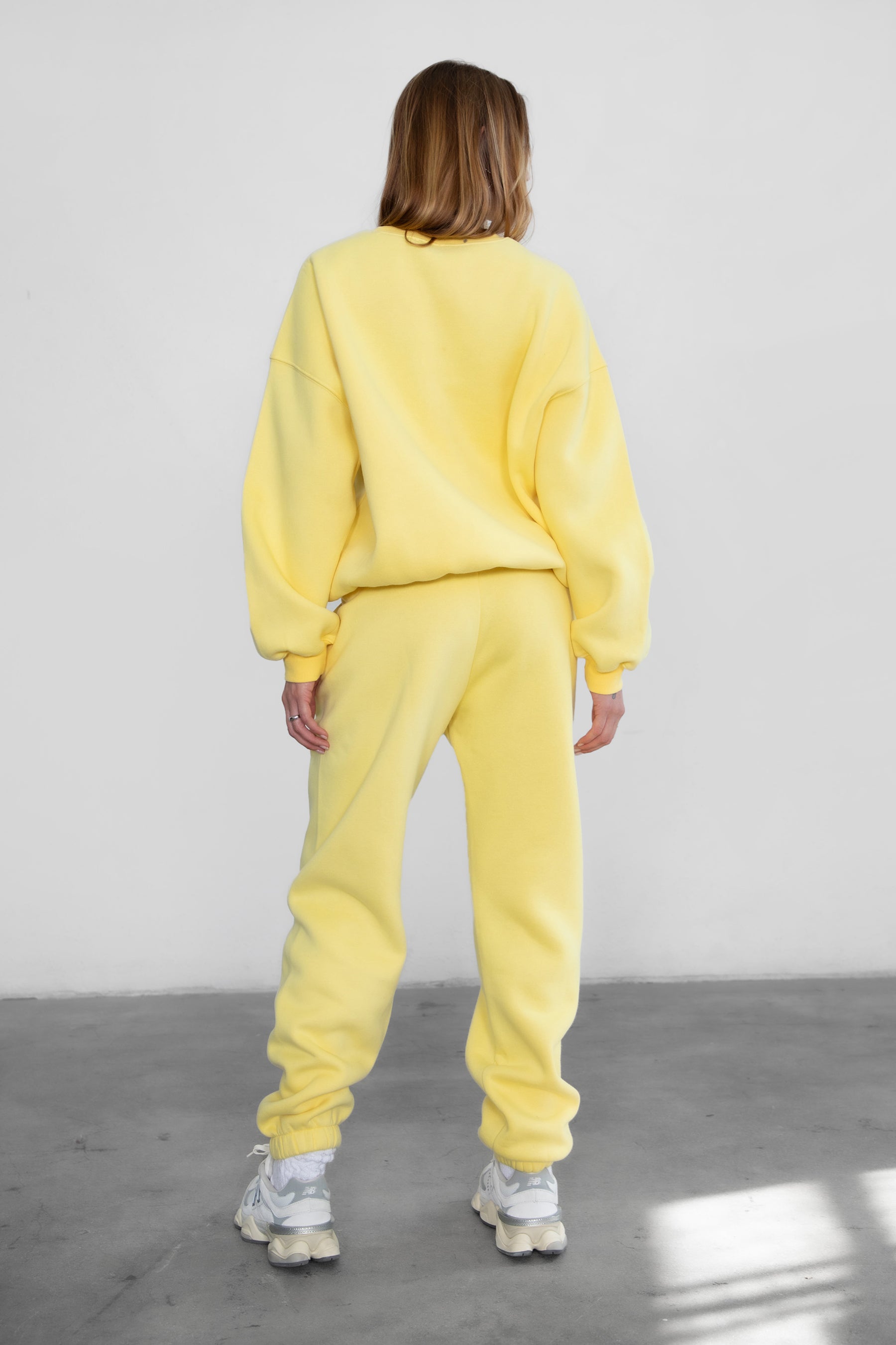 Woman wearing the TIC TOC TH28243 VARSITY yellow fleece crew neck pullover sweatshirt featuring dropped shoulders, ribbed trim, and plush fleece fabric with the matching bottoms