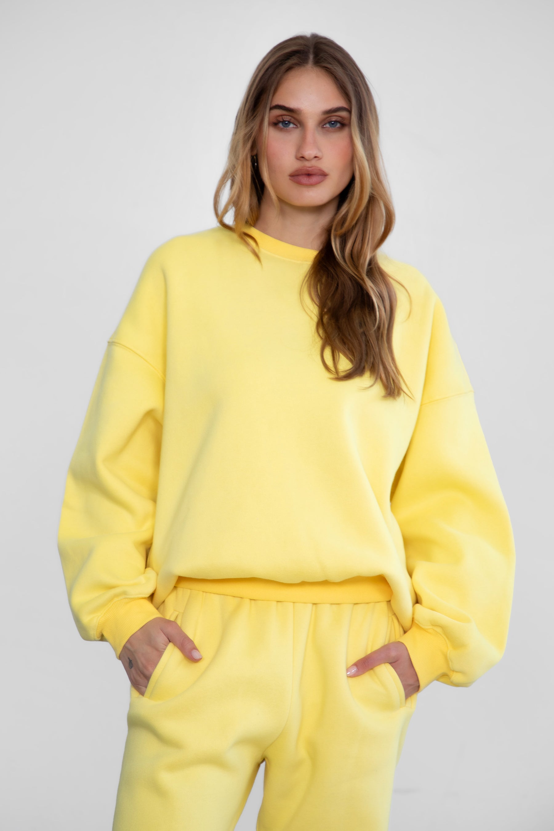 Woman wearing the TIC TOC TH28243 VARSITY yellow fleece crew neck pullover sweatshirt featuring dropped shoulders, ribbed trim, and plush fleece fabric with the matching bottoms