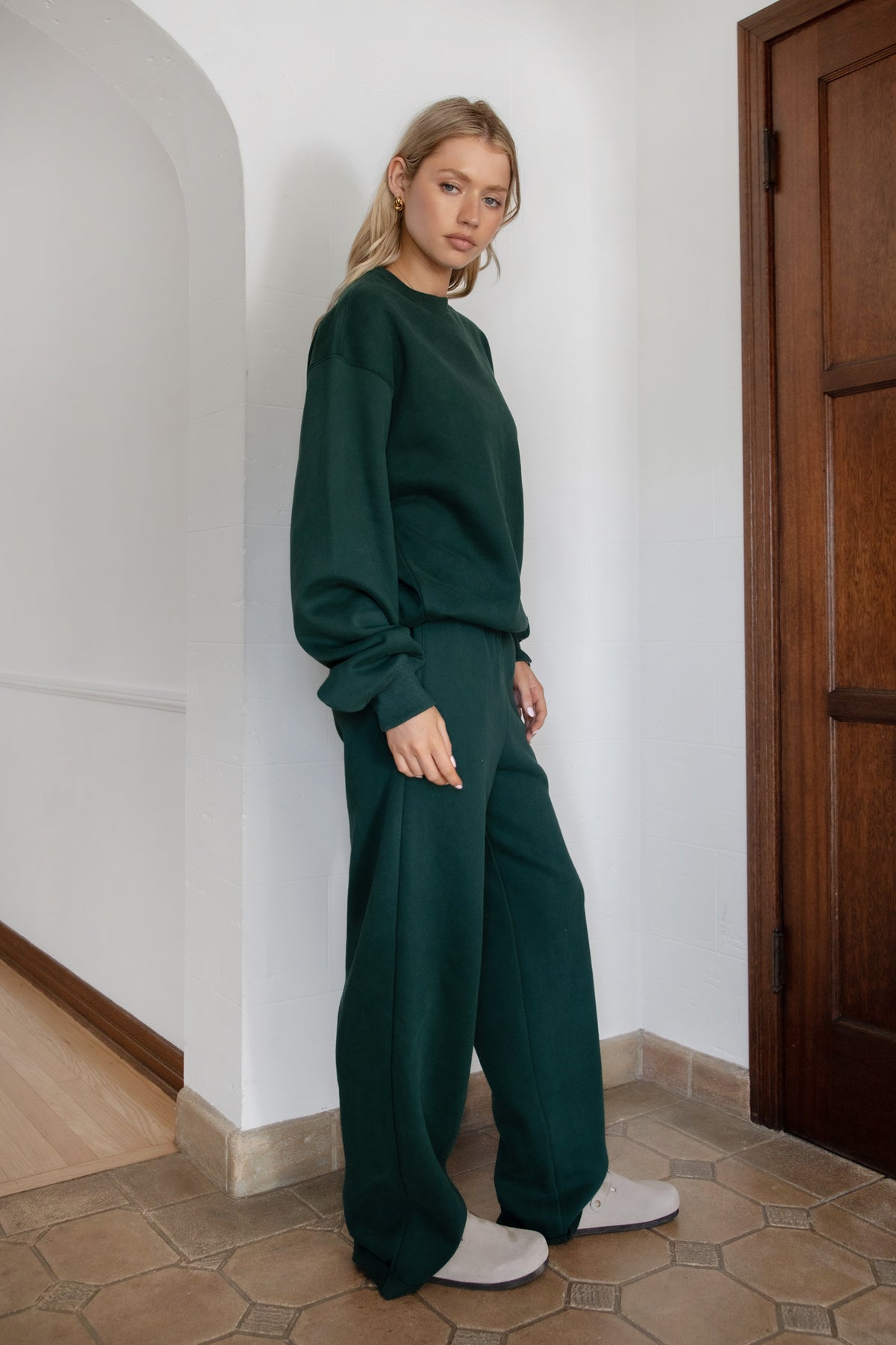 Woman wearing the TIC TOC TJ31656 LANI forrest green cloud fleece crew neck pullover sweatshirt featuring dropped shoulders, ribbed trim, and cozy fleece fabric with the matching bottoms .