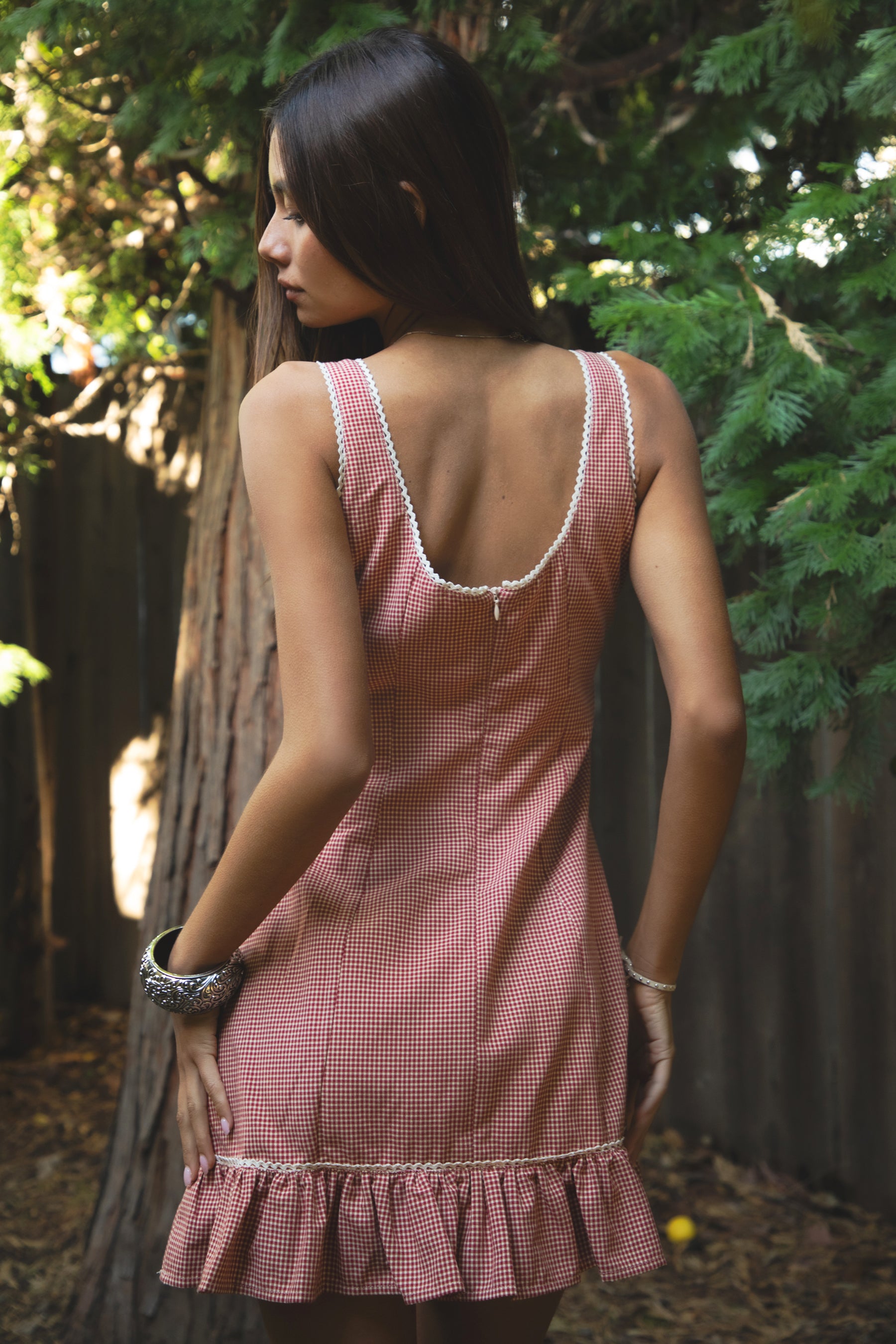 Woman wearing TIC TOC DA31931-AMELIE AMELIE gingham mini dress featuring a square scoop neckline with picot trim, wide shoulder straps, front faux button detail, fitted bodice with under bust seam, ruffled hem mini skirt in gingham poplin fabric, and a clean back zipper closure, styled with simple accessories for a coquette, western-sweet summer look.