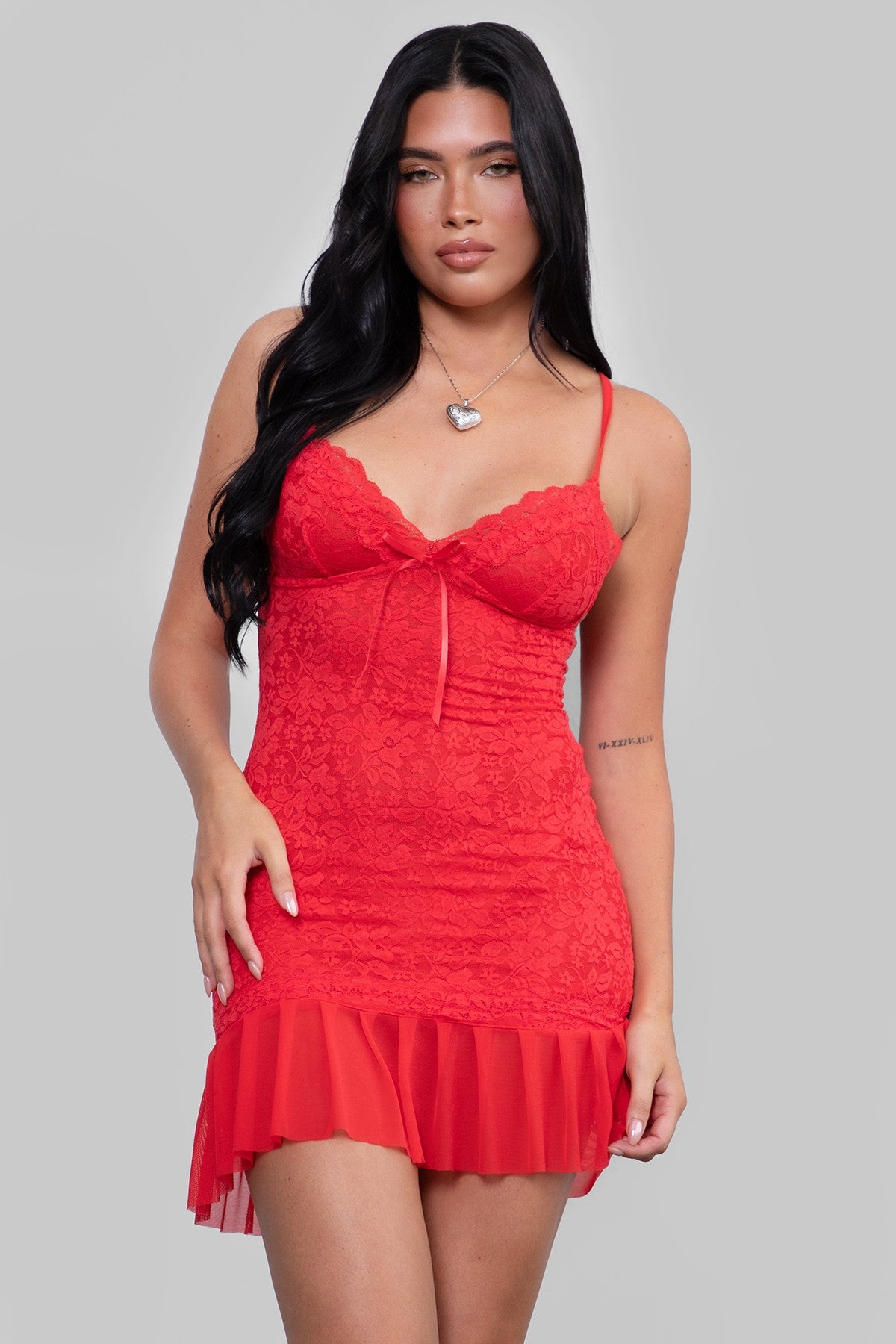 Woman in TIC TOC CARLITA Lace Bodycon Mini Dress in red featuring a deep V neckline, satin bow detail, and pleated mesh hem in a plain background setting