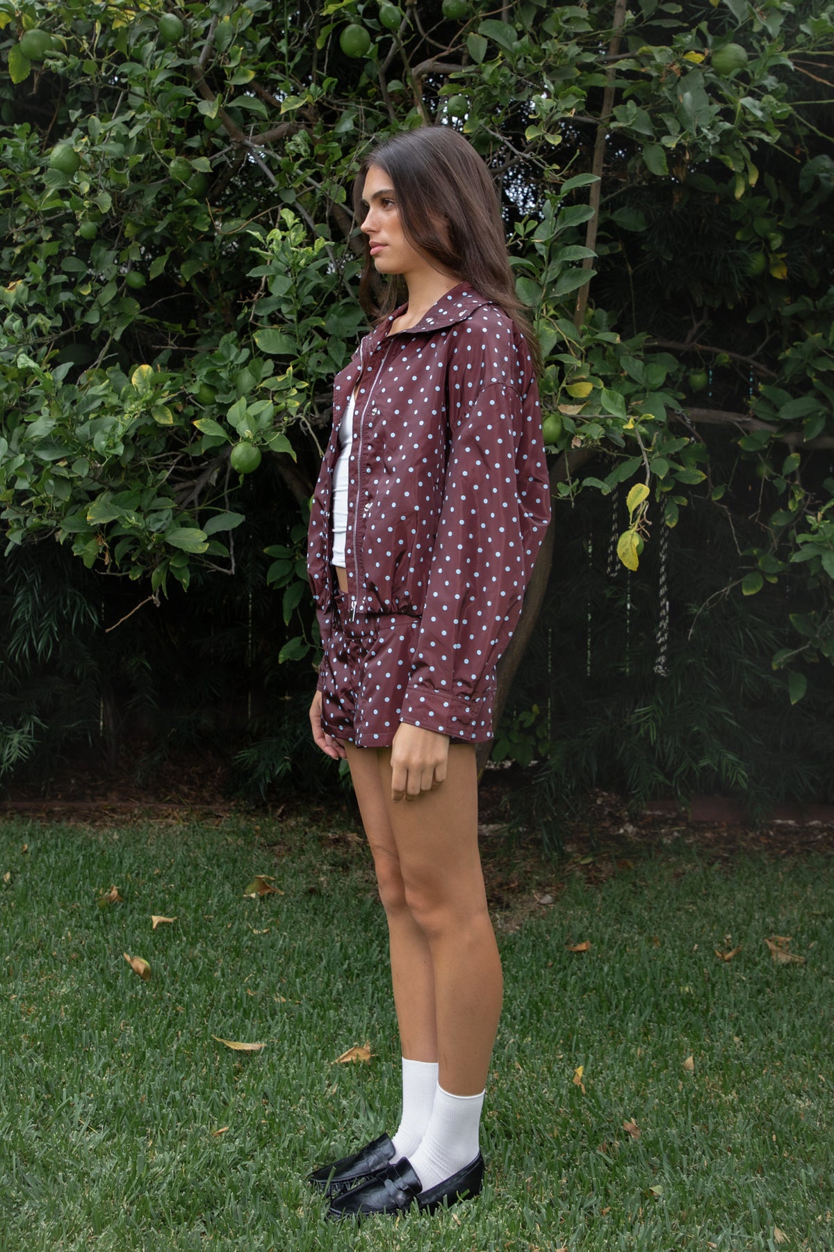 Woman wearing DOLLY polka dot low rise micro shorts featuring smooth lightweight woven polyester fabric, allover contrast polka dot print, low rise waistline, wide structured waistband with belt loops, fitted micro mini silhouette, front seam detailing, hidden front zipper closure, and full polyester lining for comfortable wear.