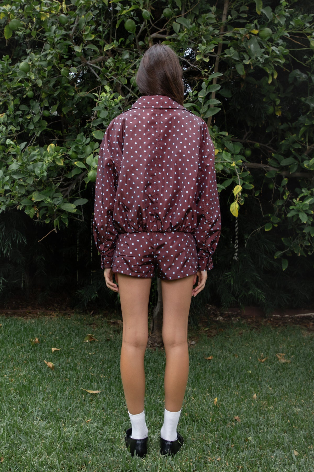 Woman wearing DOLLY polka dot low rise micro shorts featuring smooth lightweight woven polyester fabric, allover contrast polka dot print, low rise waistline, wide structured waistband with belt loops, fitted micro mini silhouette, front seam detailing, hidden front zipper closure, and full polyester lining for comfortable wear.