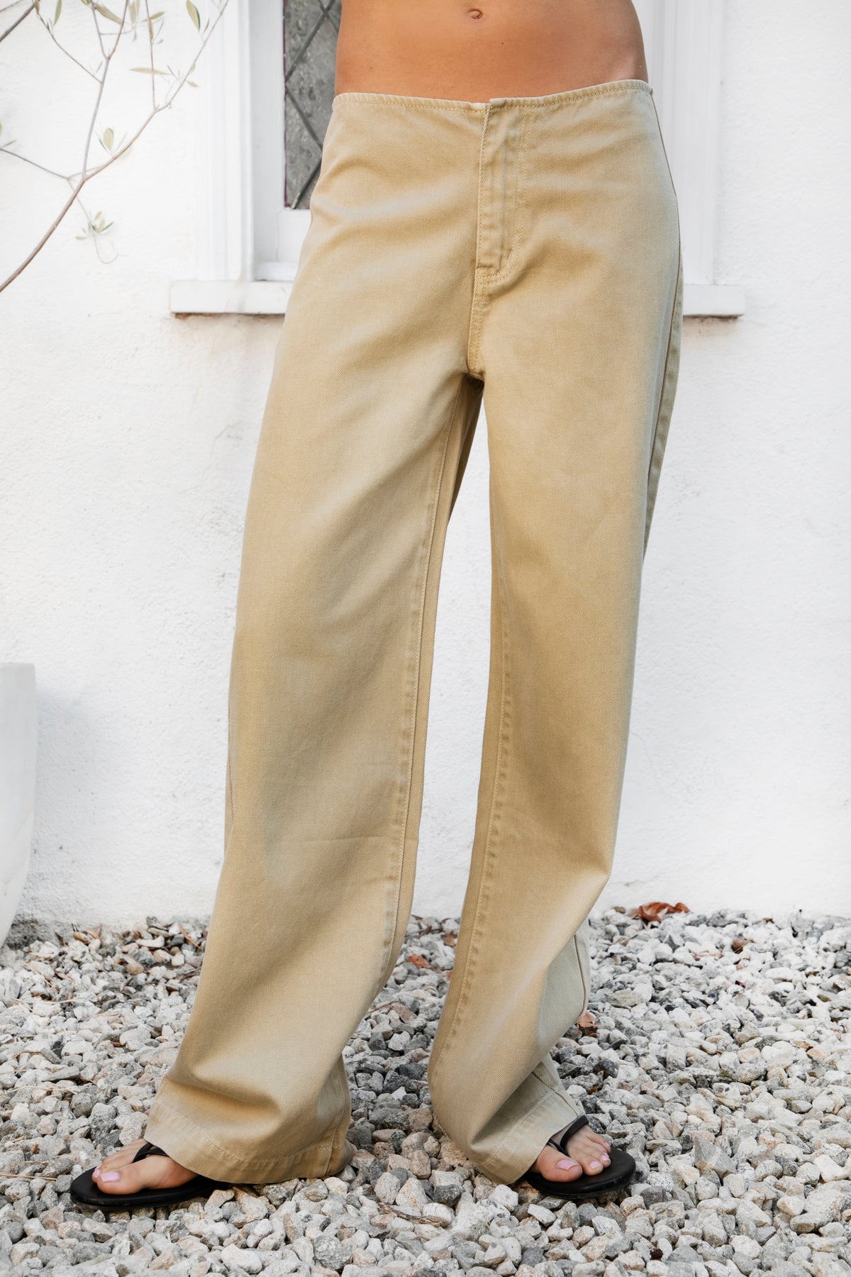 Woman wearing BOWDEN washed low rise wide leg denim pants featuring 100% cotton denim, relaxed vintage inspired silhouette, low rise waist, loose wide leg design, soft lived in washed finish, clean front styling, front zipper fly closure, classic back patch pockets, and full length fit.