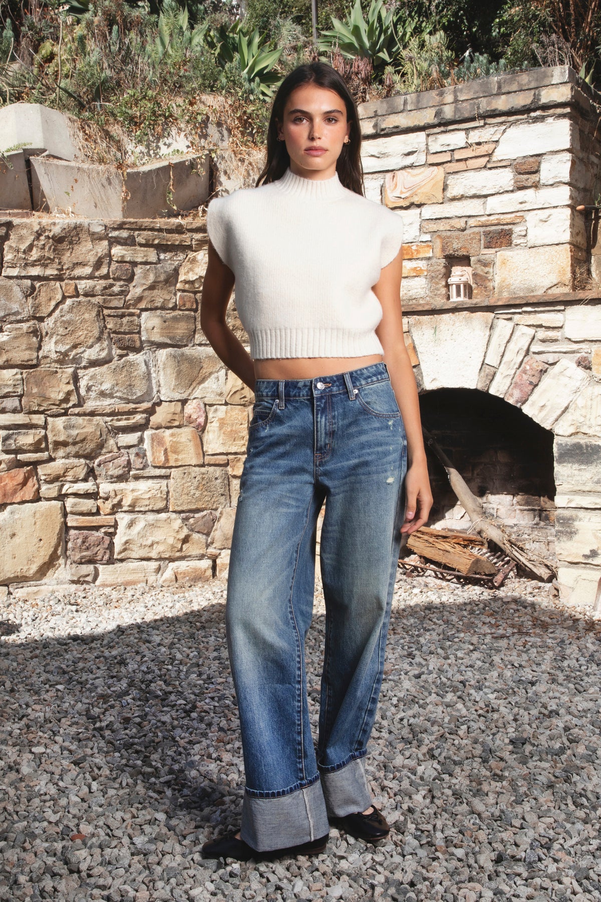 Woman wearing NEOMIE mid rise washed cuffed wide leg jeans featuring non stretch cotton denim, vintage inspired medium blue wash, subtle fading and whiskering, light distressed details, classic five pocket construction, wide straight leg silhouette, extra wide contrast cuffed hems, and button zip fly closure with belt loops.