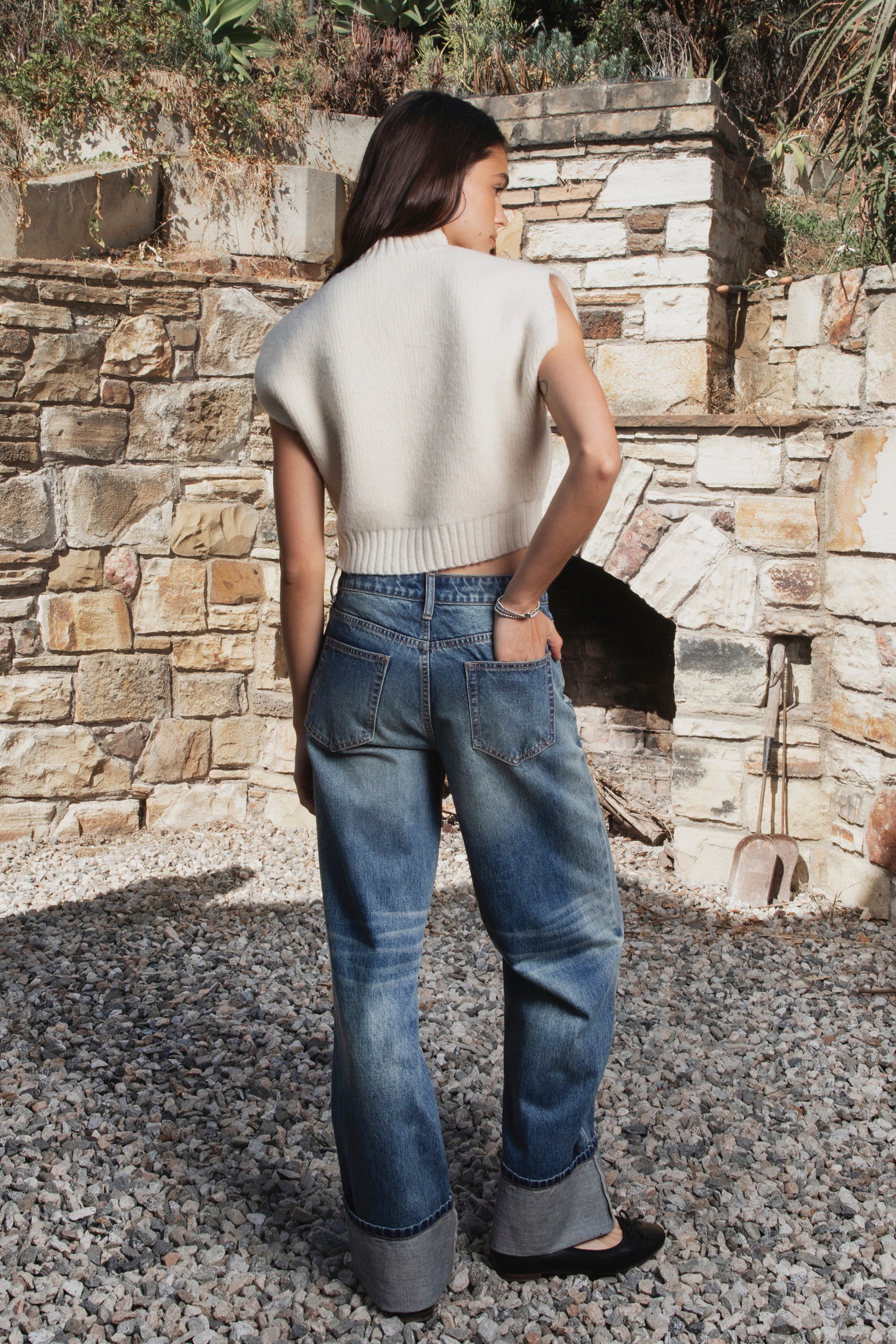Woman wearing NEOMIE mid rise washed cuffed wide leg jeans featuring non stretch cotton denim, vintage inspired medium blue wash, subtle fading and whiskering, light distressed details, classic five pocket construction, wide straight leg silhouette, extra wide contrast cuffed hems, and button zip fly closure with belt loops.