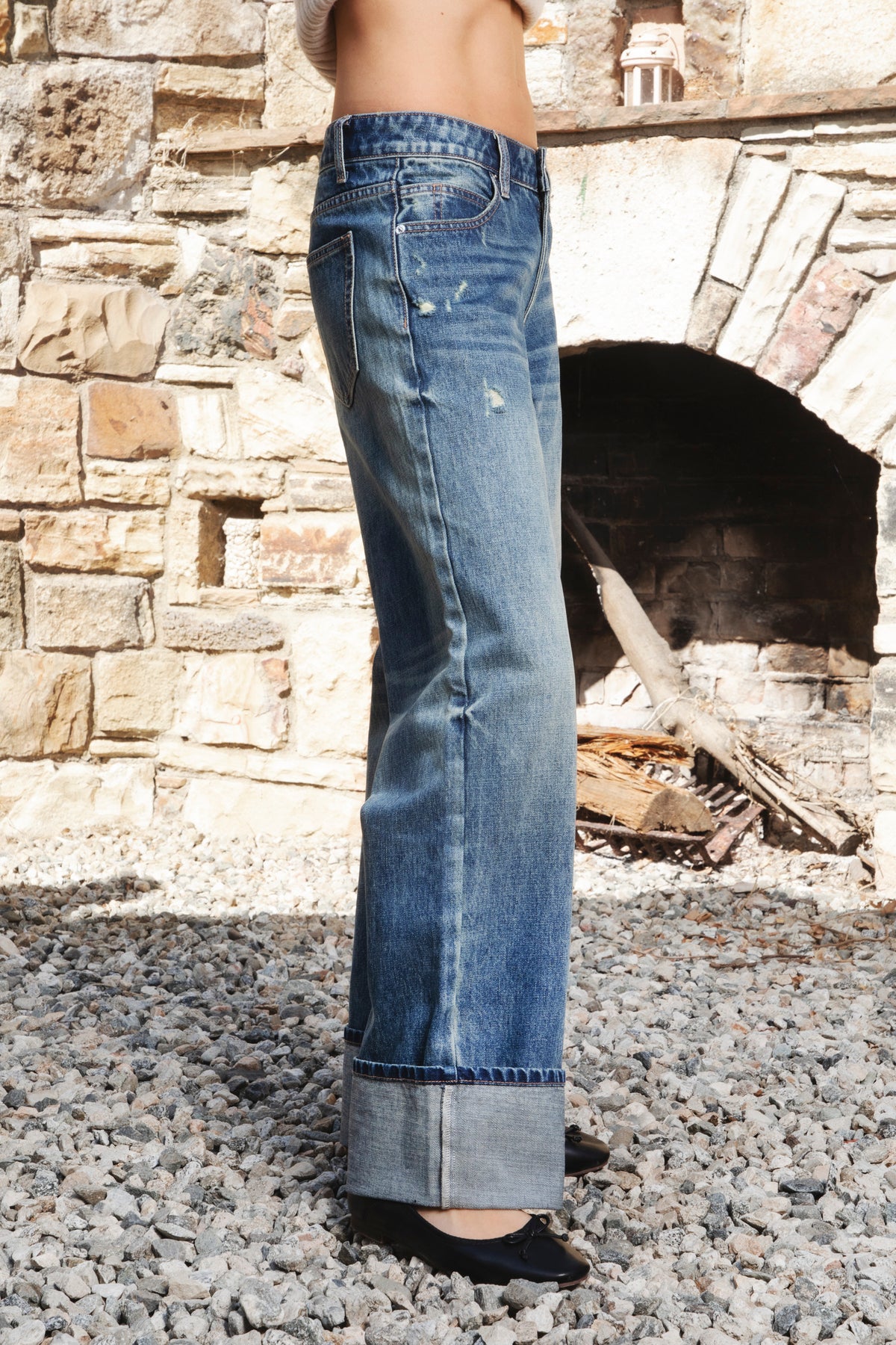 Woman wearing NEOMIE mid rise washed cuffed wide leg jeans featuring non stretch cotton denim, vintage inspired medium blue wash, subtle fading and whiskering, light distressed details, classic five pocket construction, wide straight leg silhouette, extra wide contrast cuffed hems, and button zip fly closure with belt loops.