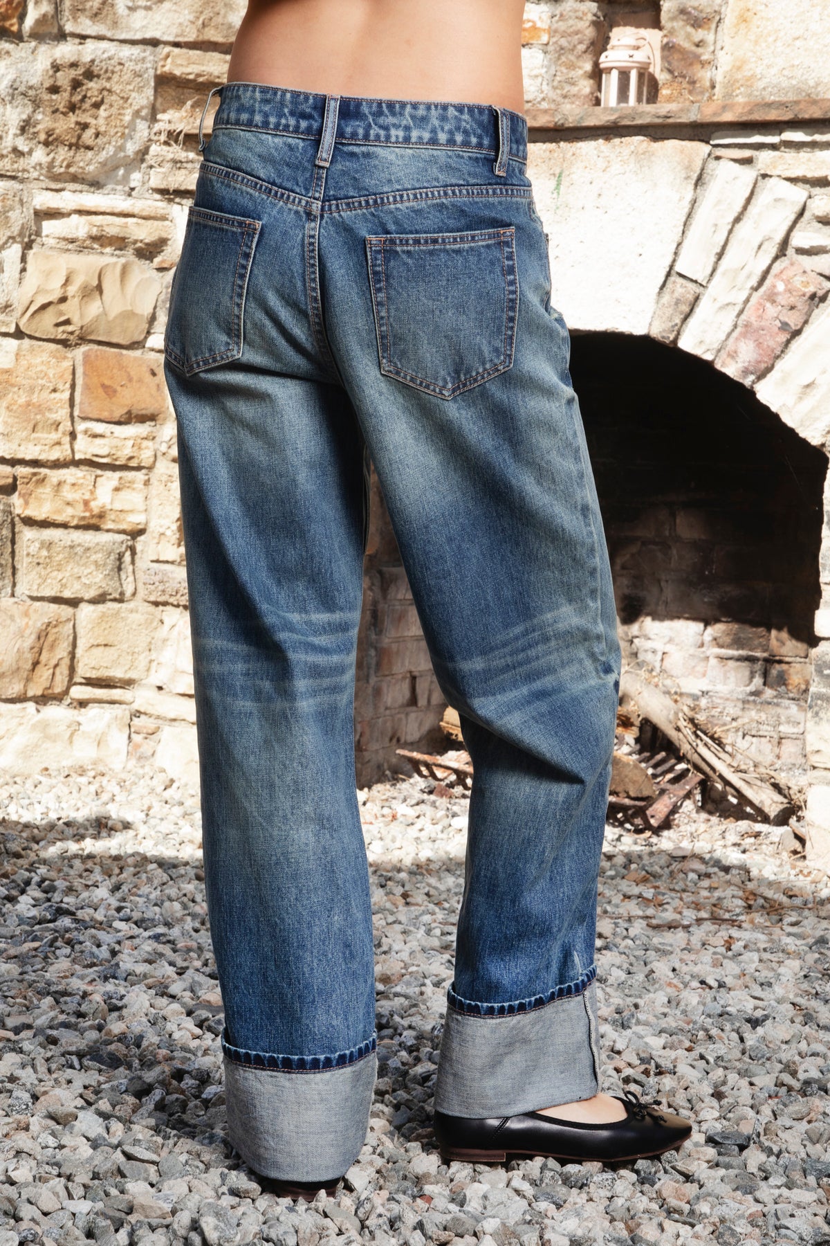 Woman wearing NEOMIE mid rise washed cuffed wide leg jeans featuring non stretch cotton denim, vintage inspired medium blue wash, subtle fading and whiskering, light distressed details, classic five pocket construction, wide straight leg silhouette, extra wide contrast cuffed hems, and button zip fly closure with belt loops.