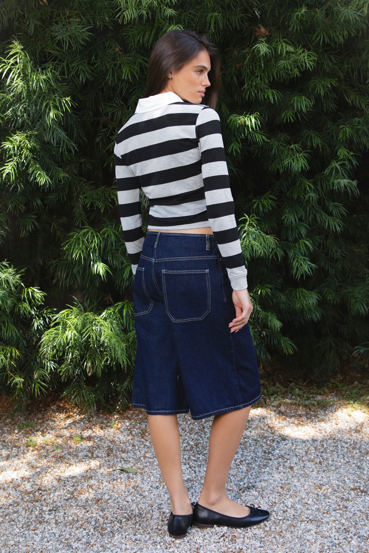 Woman wearing PIPER wide leg denim bermuda shorts featuring classic dark blue cotton blend denim fabric, mid rise waistline with belt loops, relaxed fit through the hips and thighs, wide leg knee length silhouette, front button and zipper fly closure, classic five pocket design, contrast stitching throughout, and a straight clean finished hem.