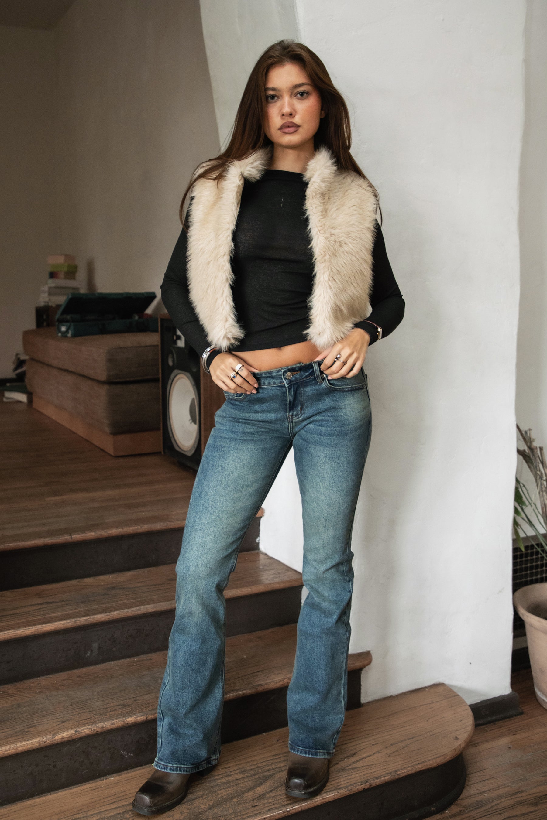 Woman wearing TIC TOC RUSTINE denim washed low rise flare jeans with vintage faded wash and long flare leg silhouette paired with boots and a western strapless top.