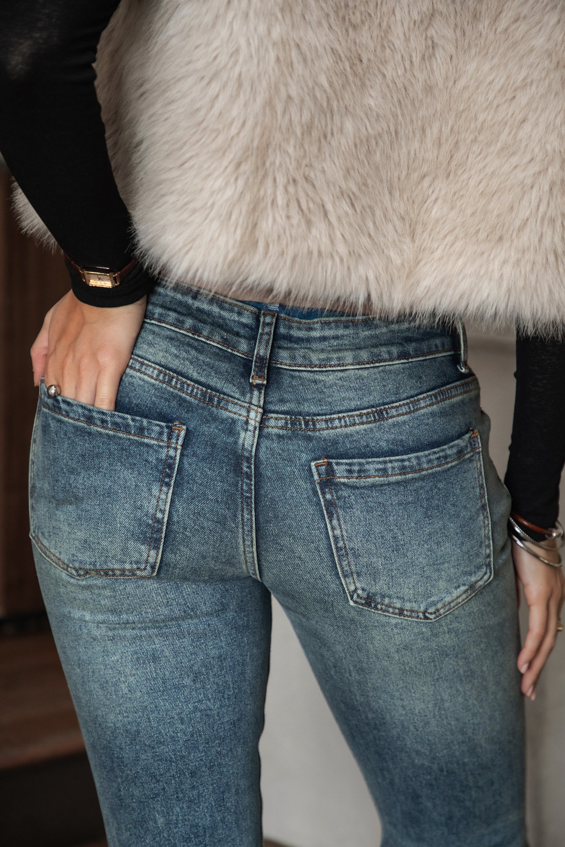 Woman wearing TIC TOC RUSTINE denim washed low rise flare jeans with vintage faded wash and long flare leg silhouette paired with boots and a western strapless top.