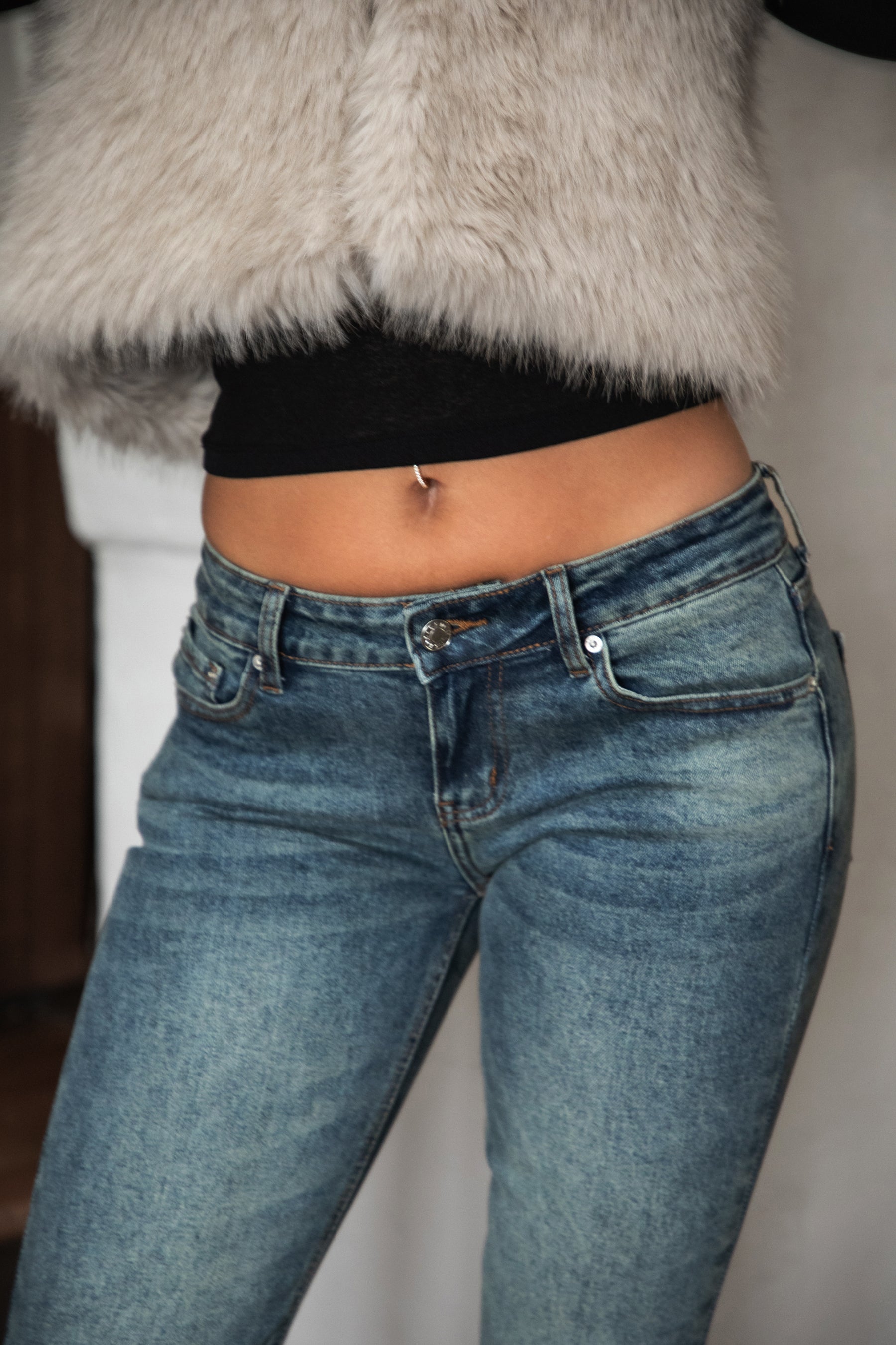 Woman wearing TIC TOC RUSTINE denim washed low rise flare jeans with vintage faded wash and long flare leg silhouette paired with boots and a western strapless top.