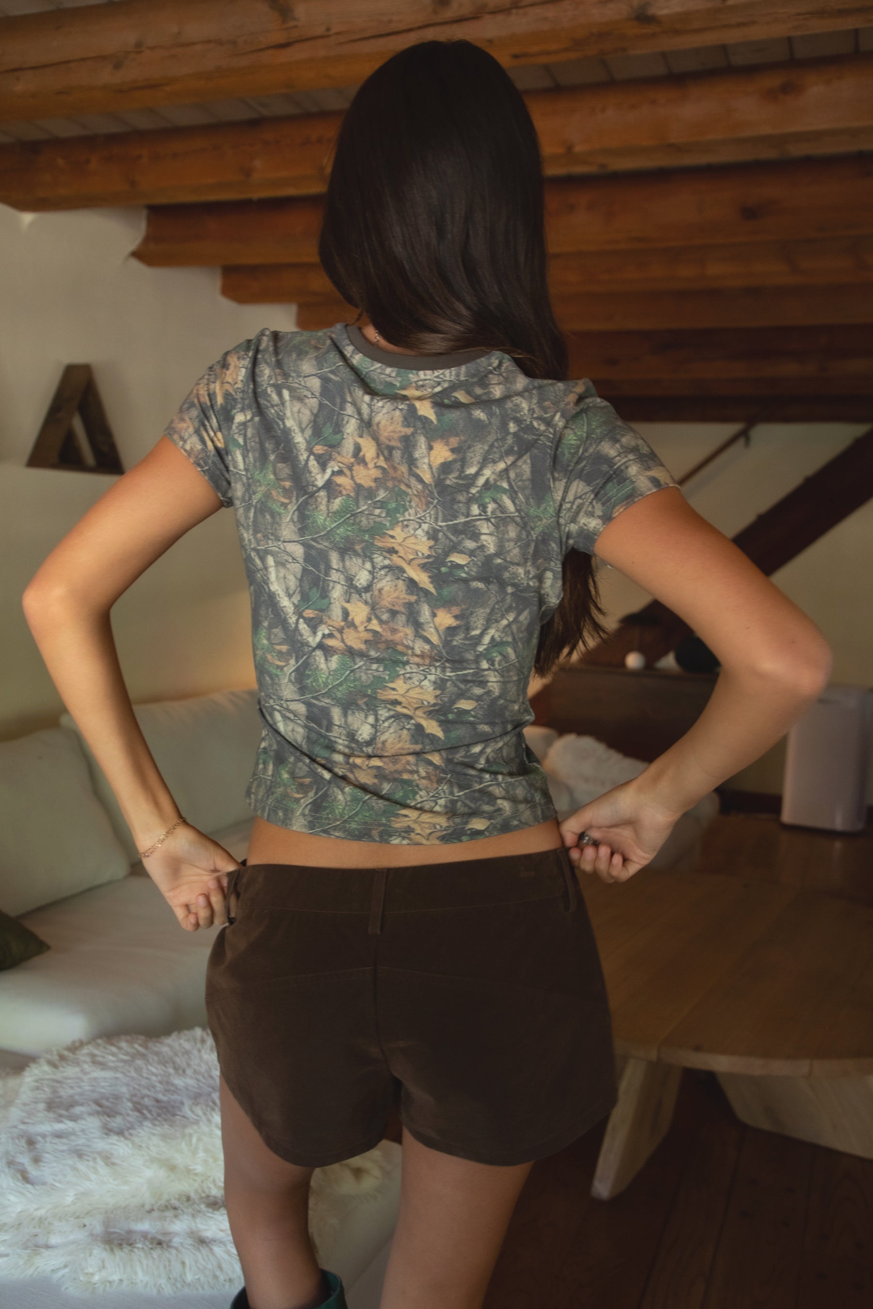 Women wearing green rain boots standing on a stone step with TIC TOC RIDER Lace-Up Faux Suede Brown Shorts with belt loops, exposed seams, and relaxed leg fit in a living room