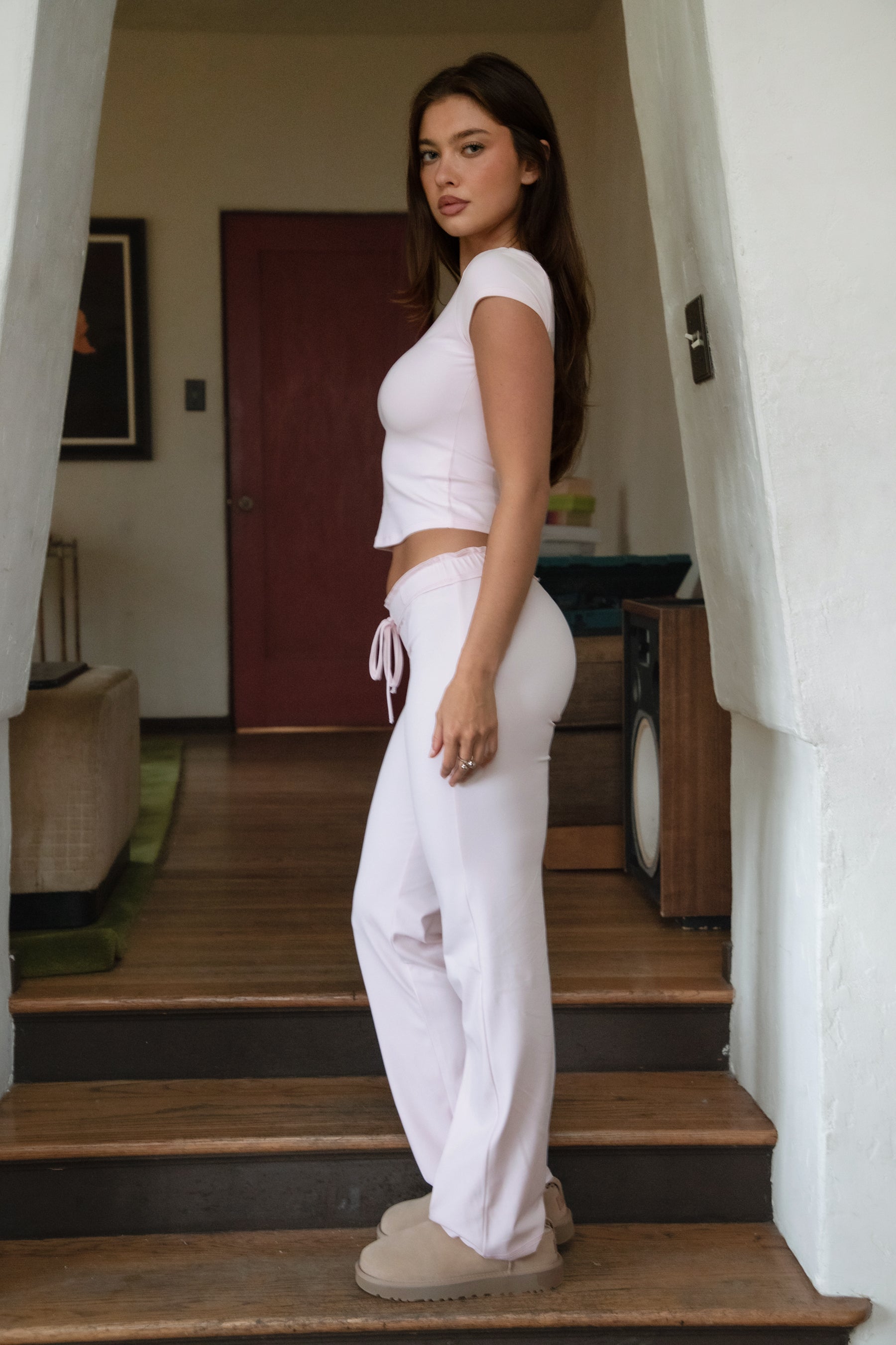 Woman wearing TIC TOC PH31905BA-NYLEE-WL navy NYLEE WL wide leg pants made from soft span jersey fabric, featuring a high-stretch body-hugging fit through the hips, foldover waistband with tie detail, and full-length wide leg silhouette, styled indoors with a matching top for a coordinated lounge/athleisure look.