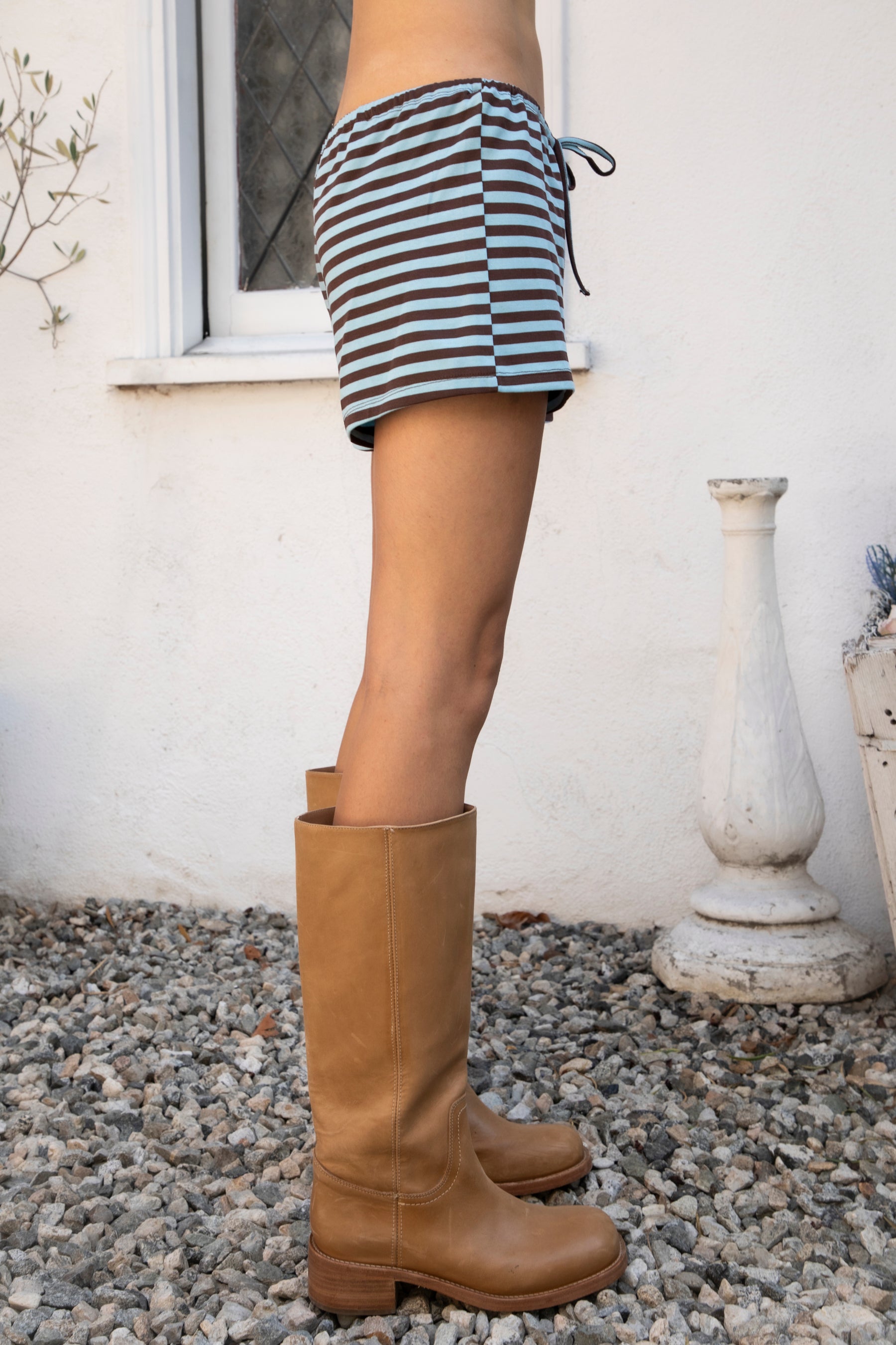 Woman wearing MARLOWE stripe mid waist drawstring stretch shorts featuring an allover stripe pattern, adjustable drawstring waistband, micro shorts length, relaxed easy fit silhouette, and soft stretch jersey fabric for cozy casual lounge styling.