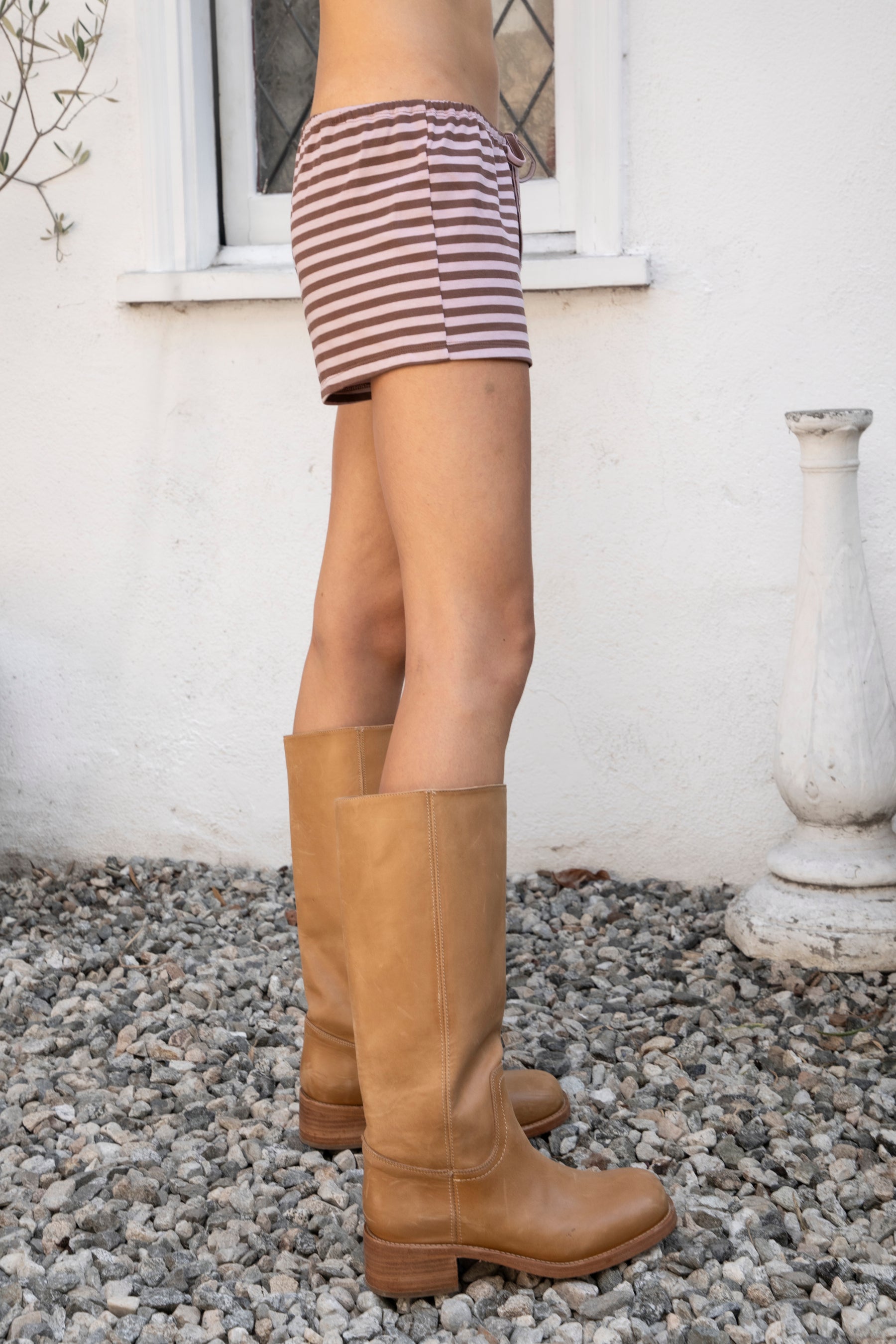 Woman wearing MARLOWE stripe mid waist drawstring stretch shorts featuring an allover stripe pattern, adjustable drawstring waistband, micro shorts length, relaxed easy fit silhouette, and soft stretch jersey fabric for cozy casual lounge styling.