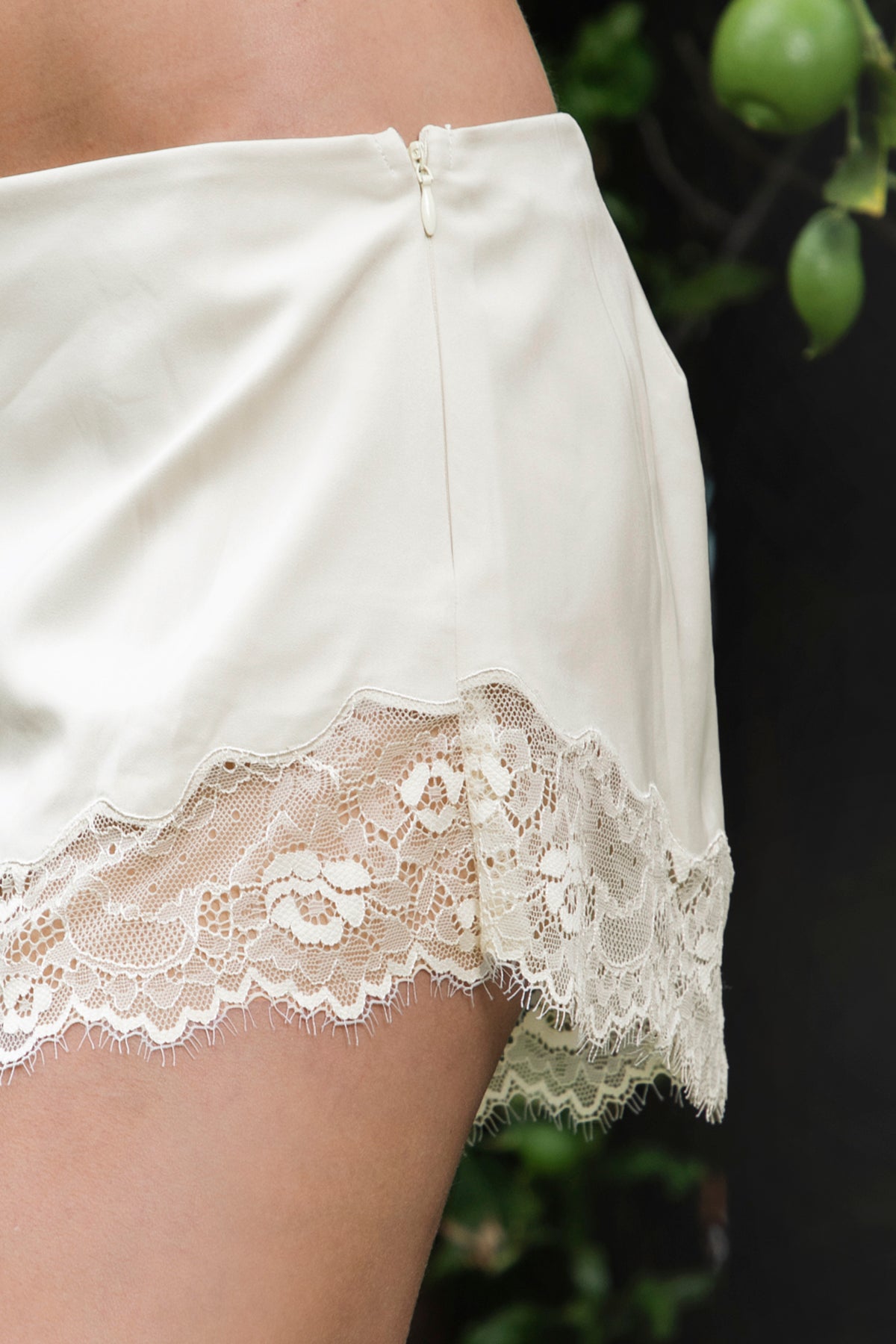 Woman wearing LUNETTE scalloped eyelash lace trim satin shorts featuring soft stretch satin fabric, high rise waist, clean tailored finish, delicate scalloped eyelash lace trim along the hem, hidden back zipper closure, and fully lined interior for added comfort and coverage.