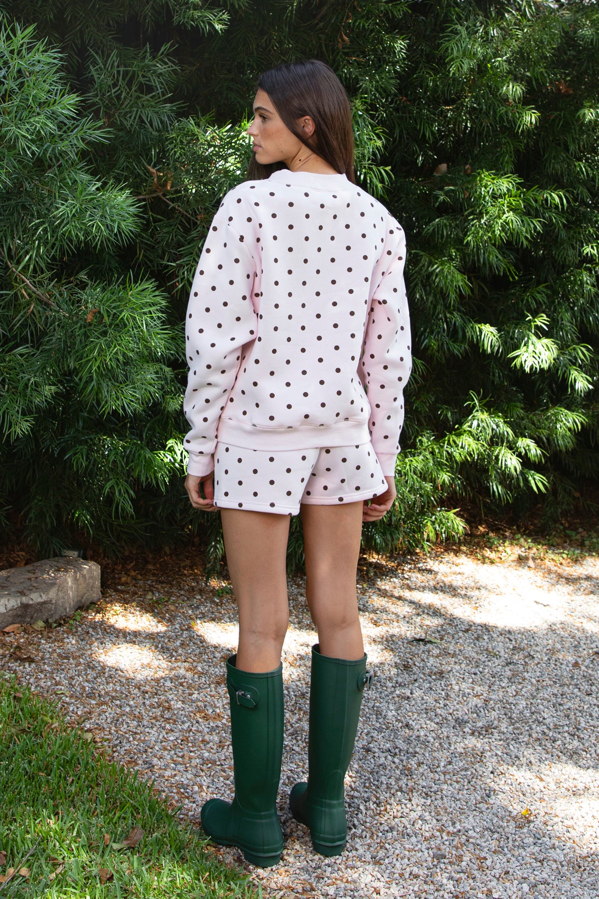 Woman wearing PIPPA polka dot plush fleece shorts featuring soft cotton blend fleece fabric, playful polka dot print, comfortable elastic waistband, easy pull on design, relaxed fit through the hips and legs, functional side pockets, short length, and clean finished hems designed to pair with the matching PIPPA sweatshirt.