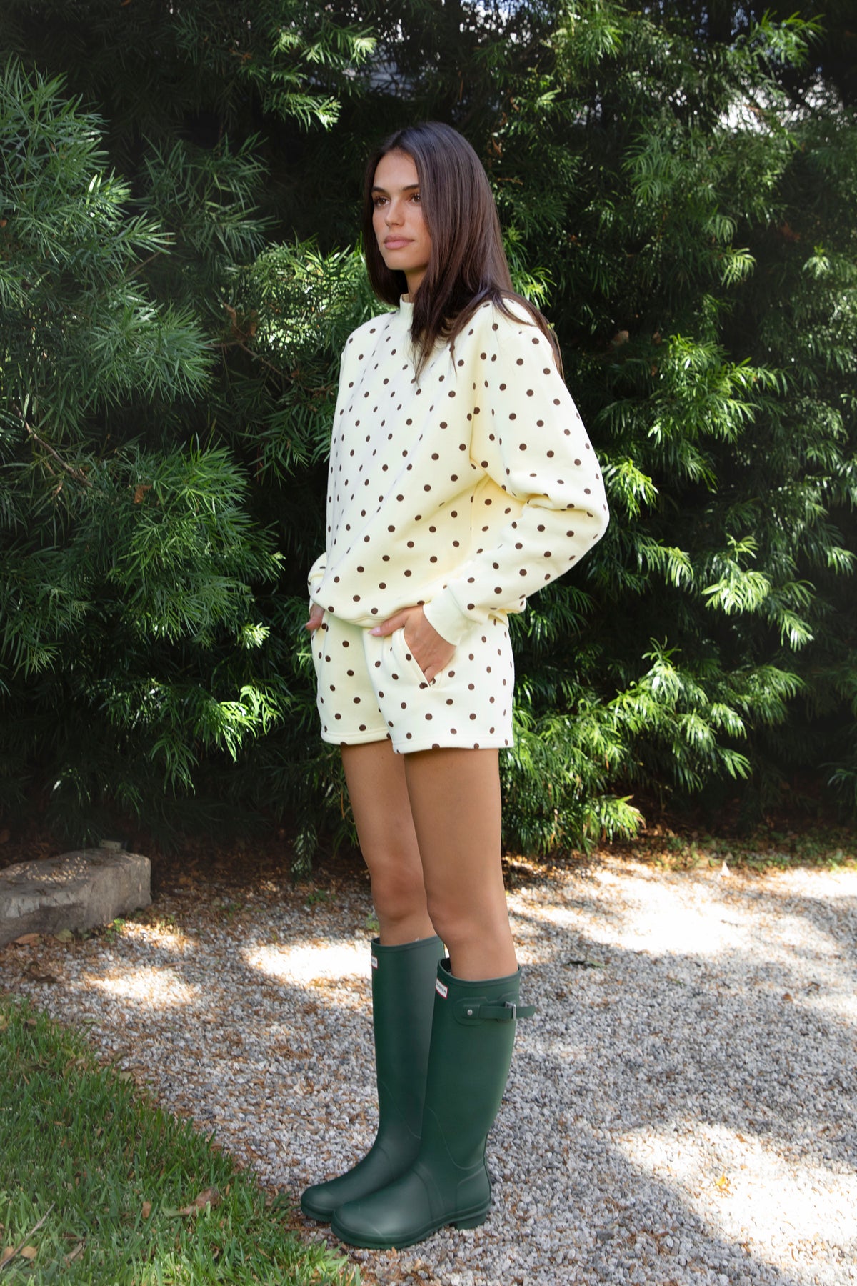 Woman wearing PIPPA polka dot plush fleece shorts featuring soft cotton blend fleece fabric, playful polka dot print, comfortable elastic waistband, easy pull on design, relaxed fit through the hips and legs, functional side pockets, short length, and clean finished hems designed to pair with the matching PIPPA sweatshirt.