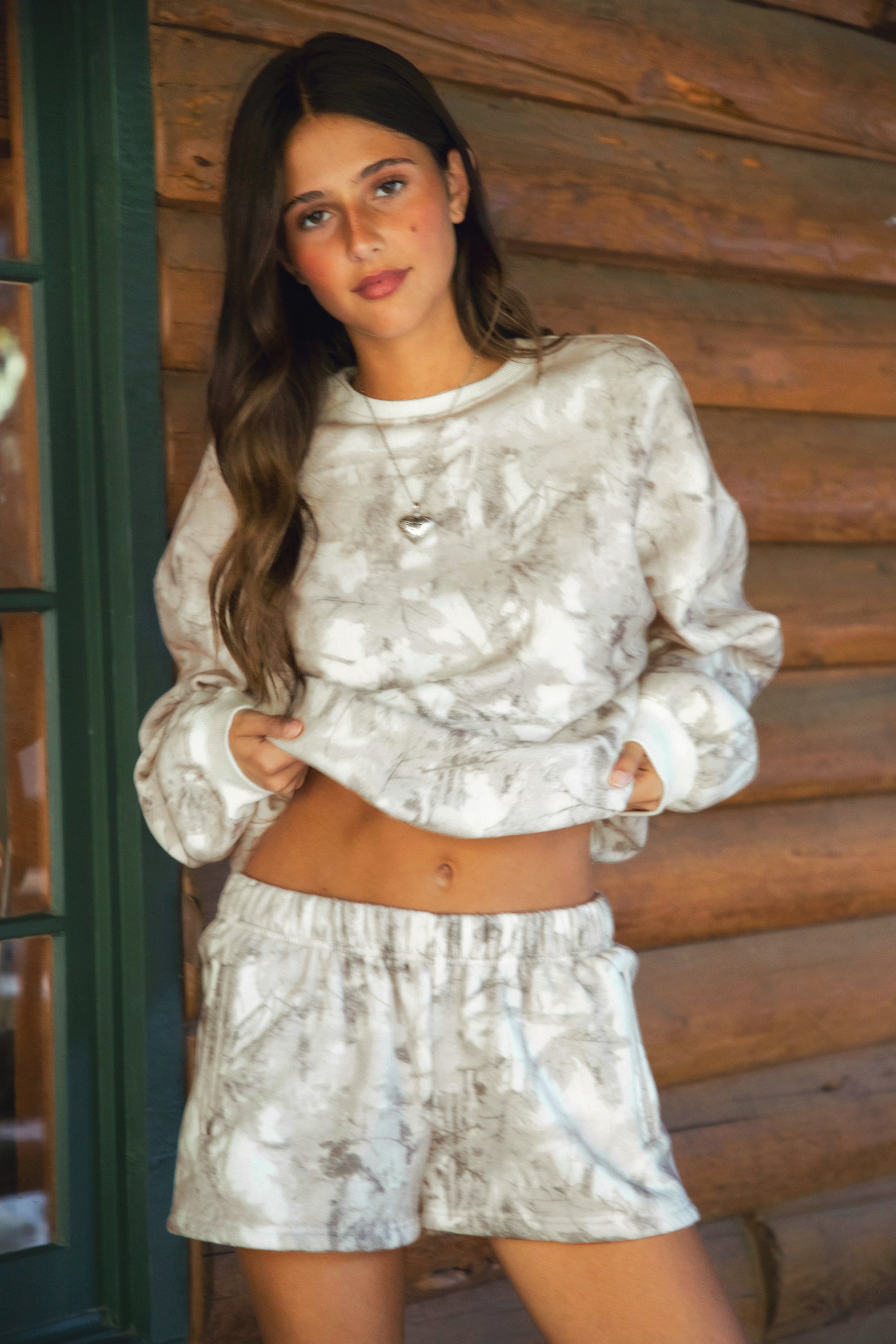 Person wearing a woodland camo outfit with beige slippers standing on a wooden deck.