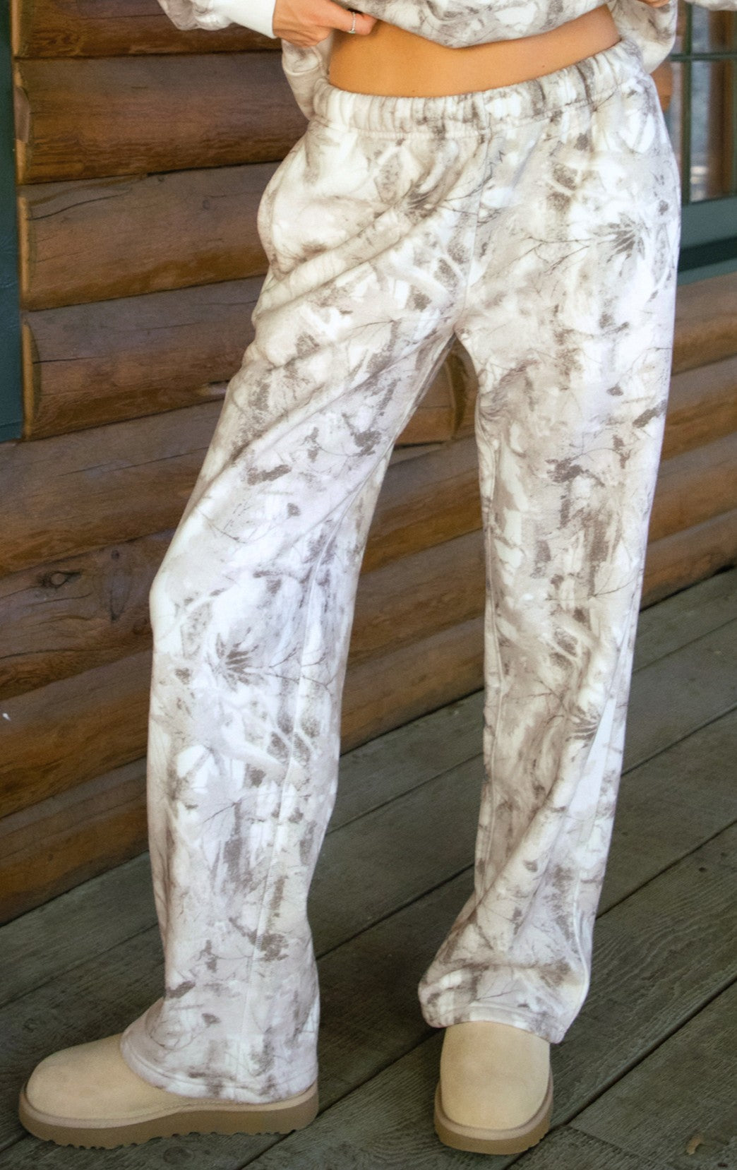 Women wearing TIC TOC AVERY Woodland Camo Wide Leg Sweatpants with elastic waistband, drawcord, in a soft Cloud Fleece fabric in a cabin